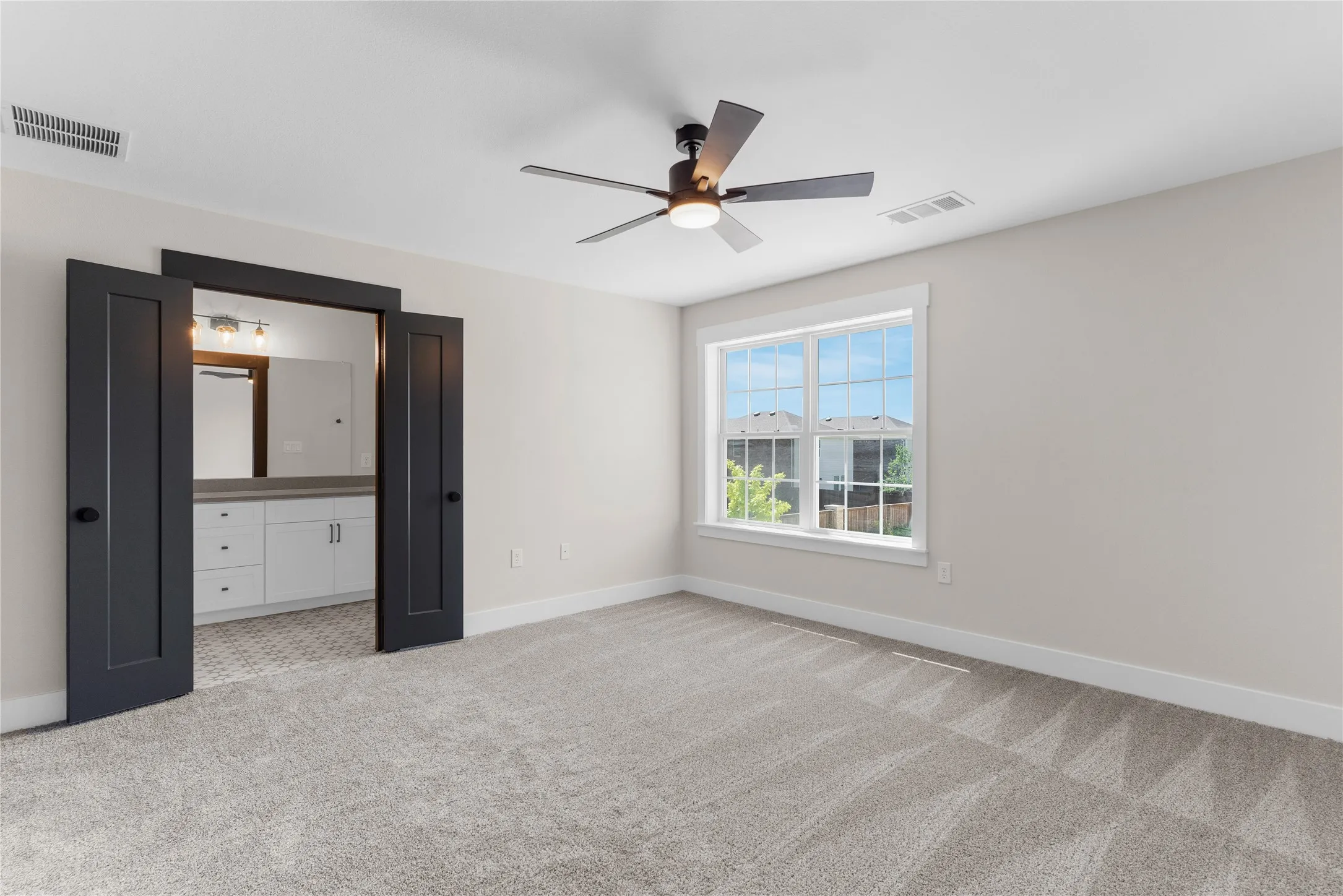 Carpeted room with a ceiling fan light fixture and a multi-pane window
