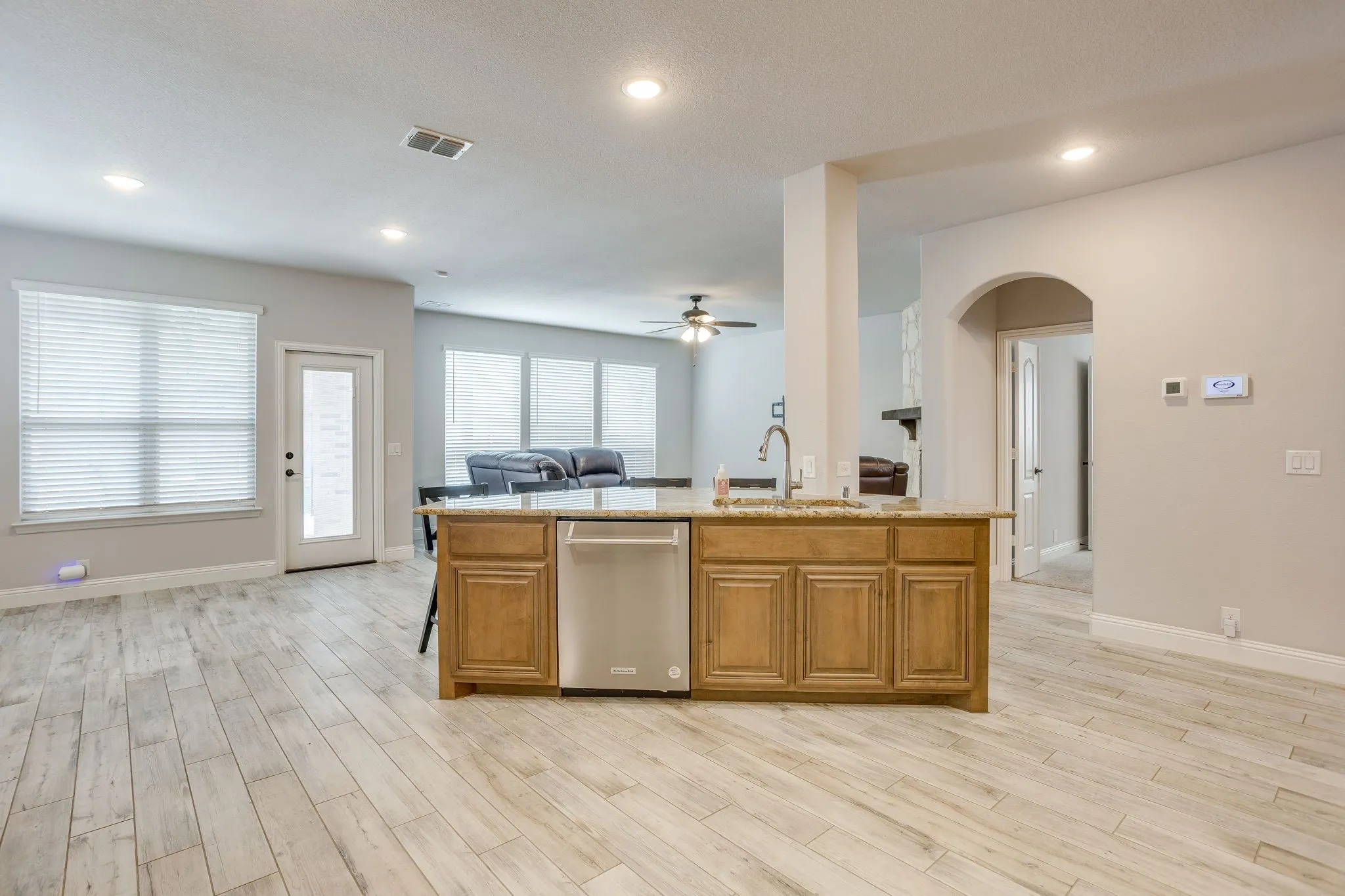 Kitchen island featuring a double-basin sink with a gooseneck faucet, light-toned cabinetry, and an integrated dishwasher