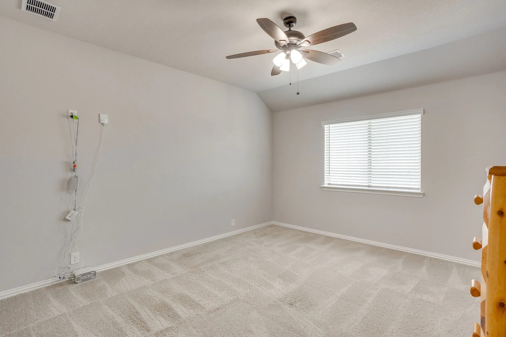 Carpeted room featuring a ceiling fan with integrated lighting, a window with horizontal blinds, and neutral wall paint