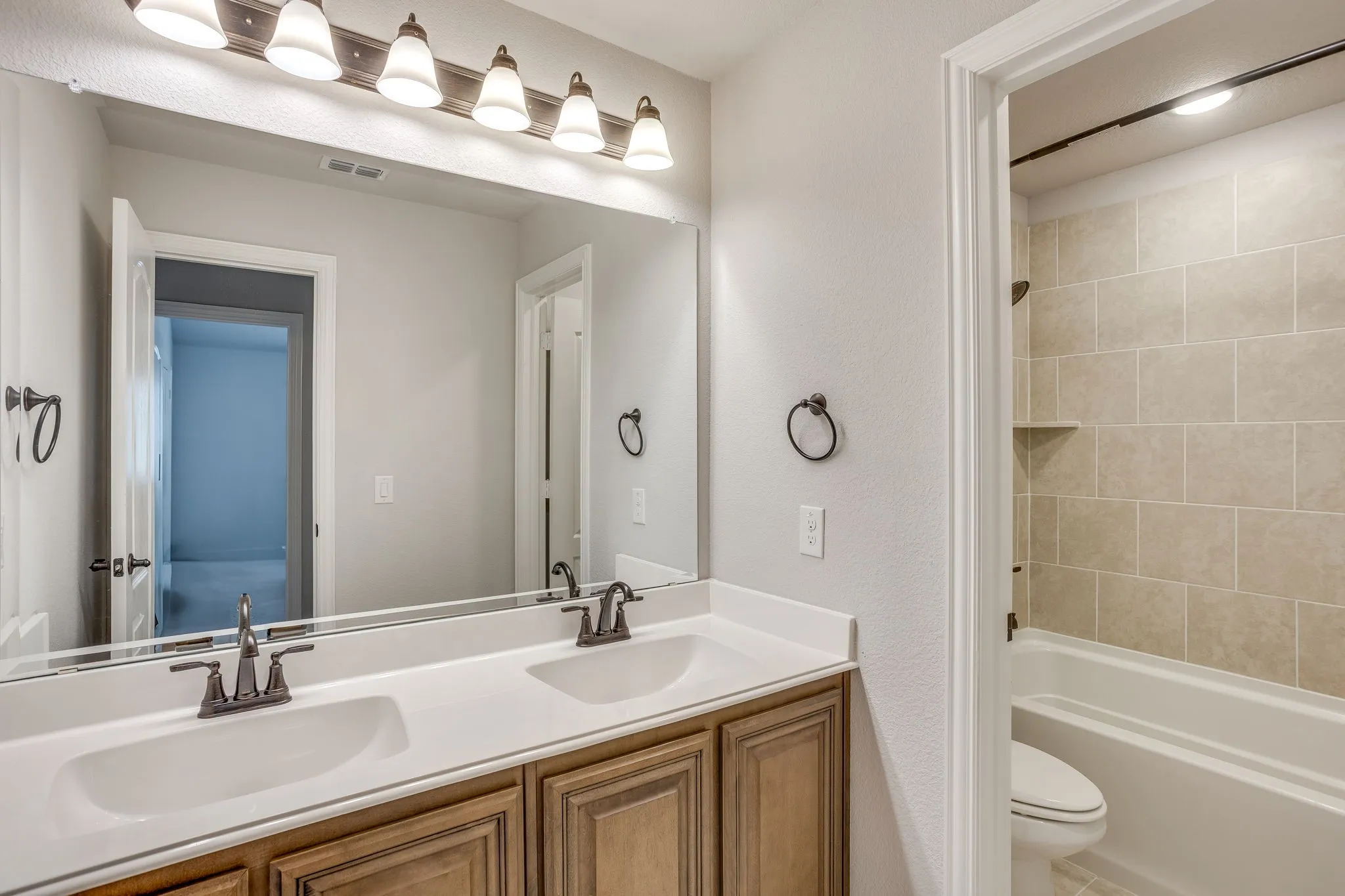 Double vanity with individual sinks, bronze-finish fixtures, and overhead lighting
