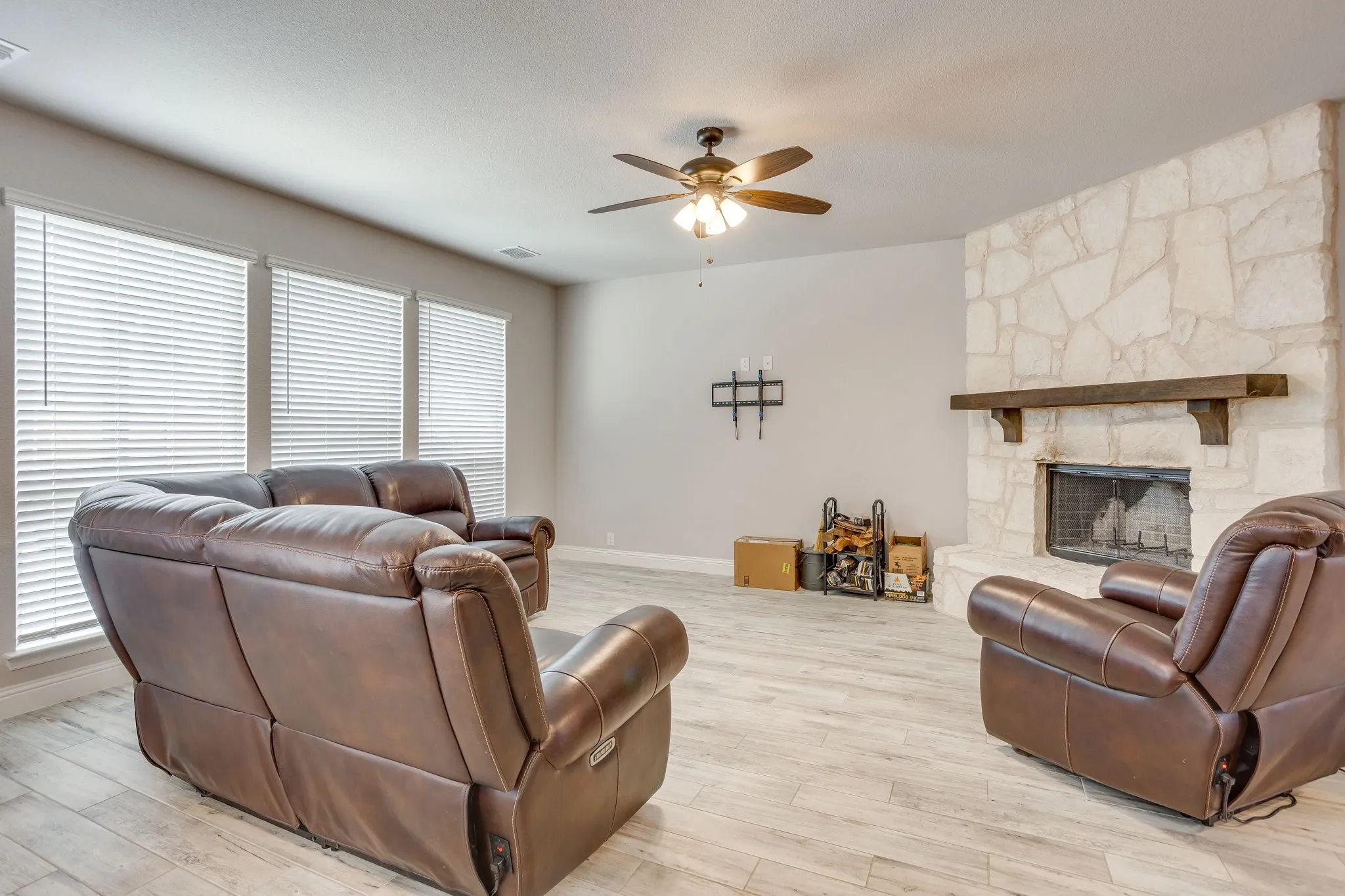 Spacious living area featuring a floor-to-ceiling stone fireplace with a substantial wood mantle