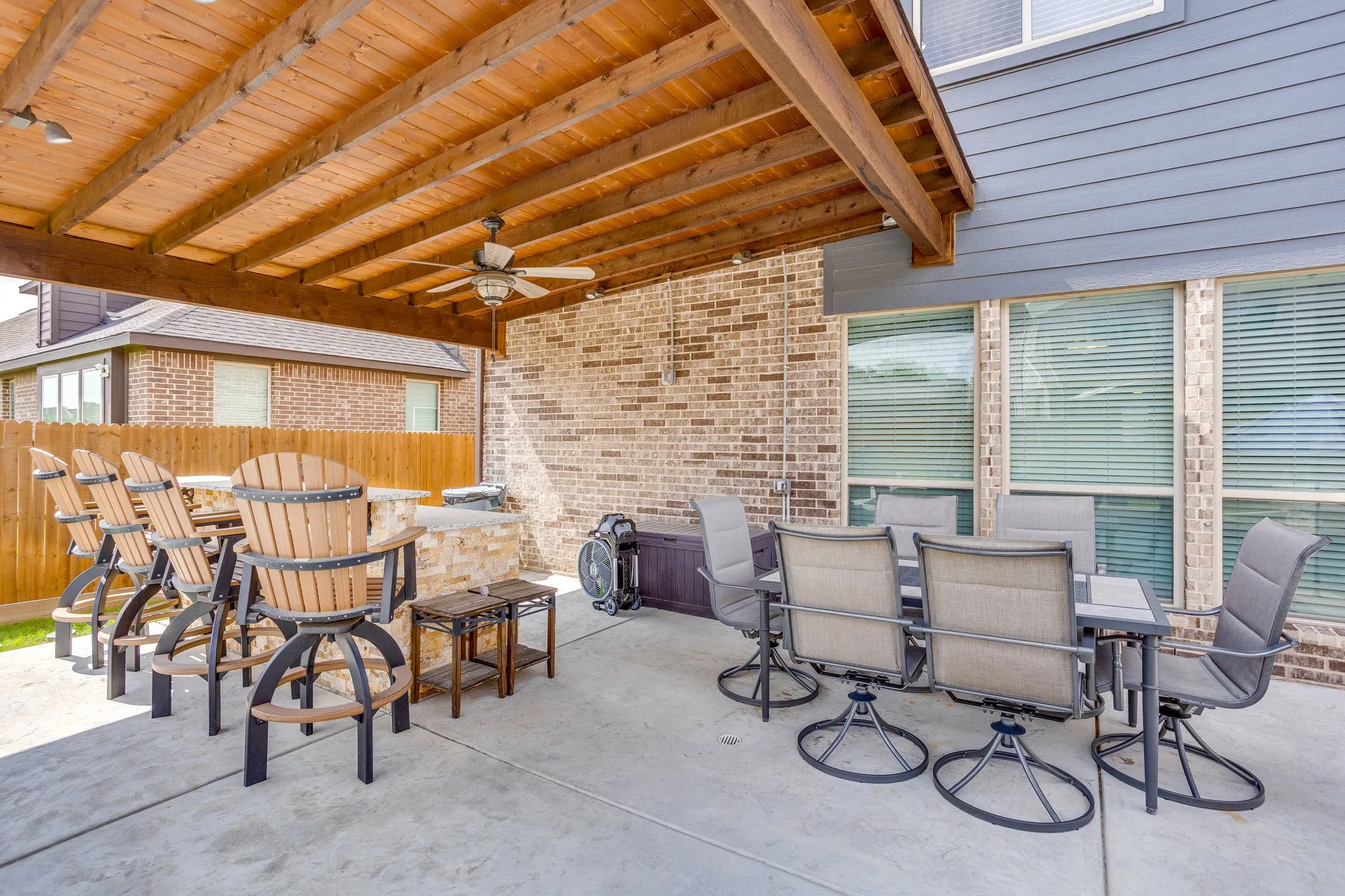 Expansive covered patio featuring a wood-beam ceiling with exposed rafters and a ceiling fan