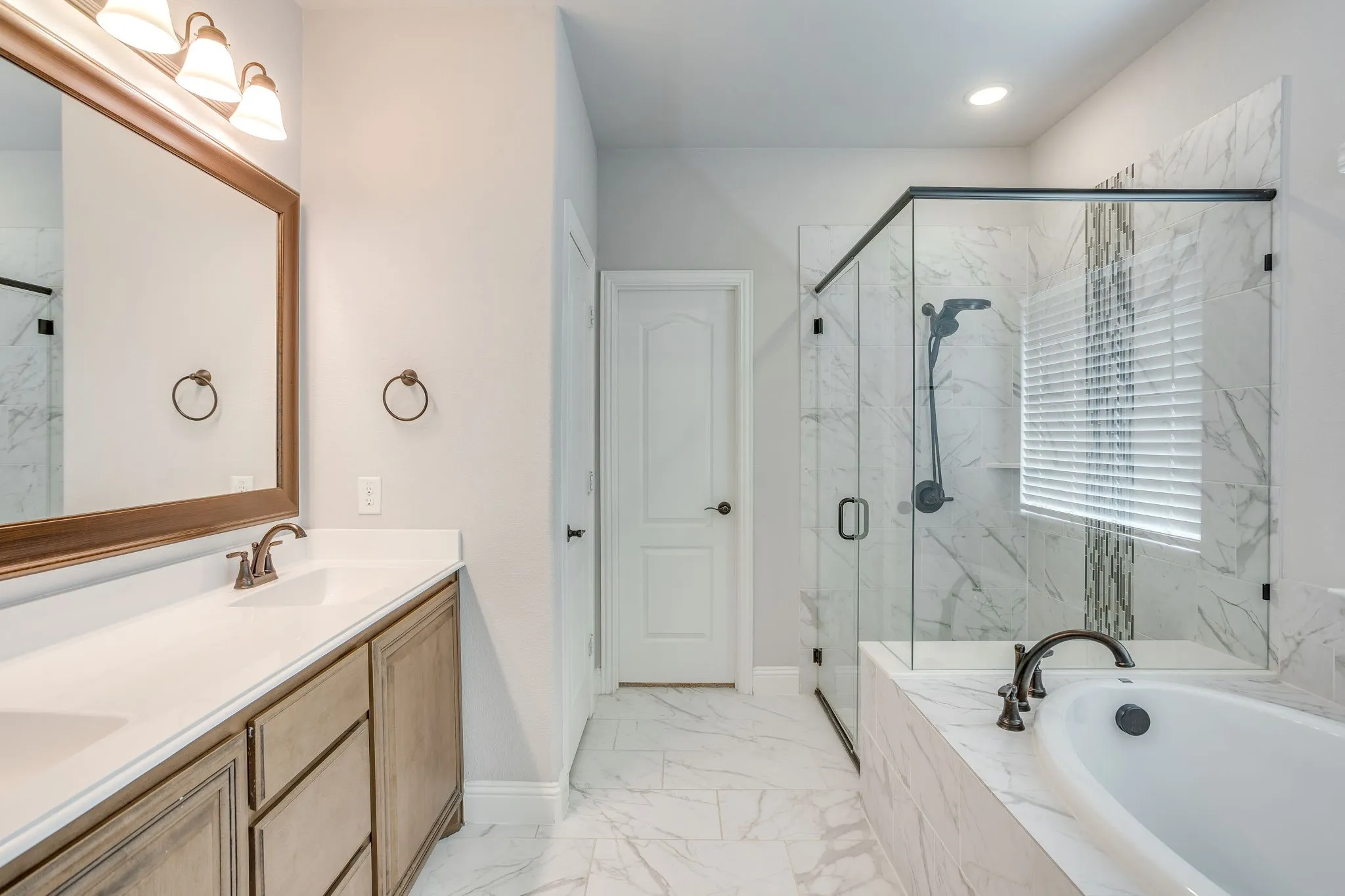 Spacious bathroom featuring a dual vanity with white countertop, a large soaking tub, and a separate glass-enclosed shower