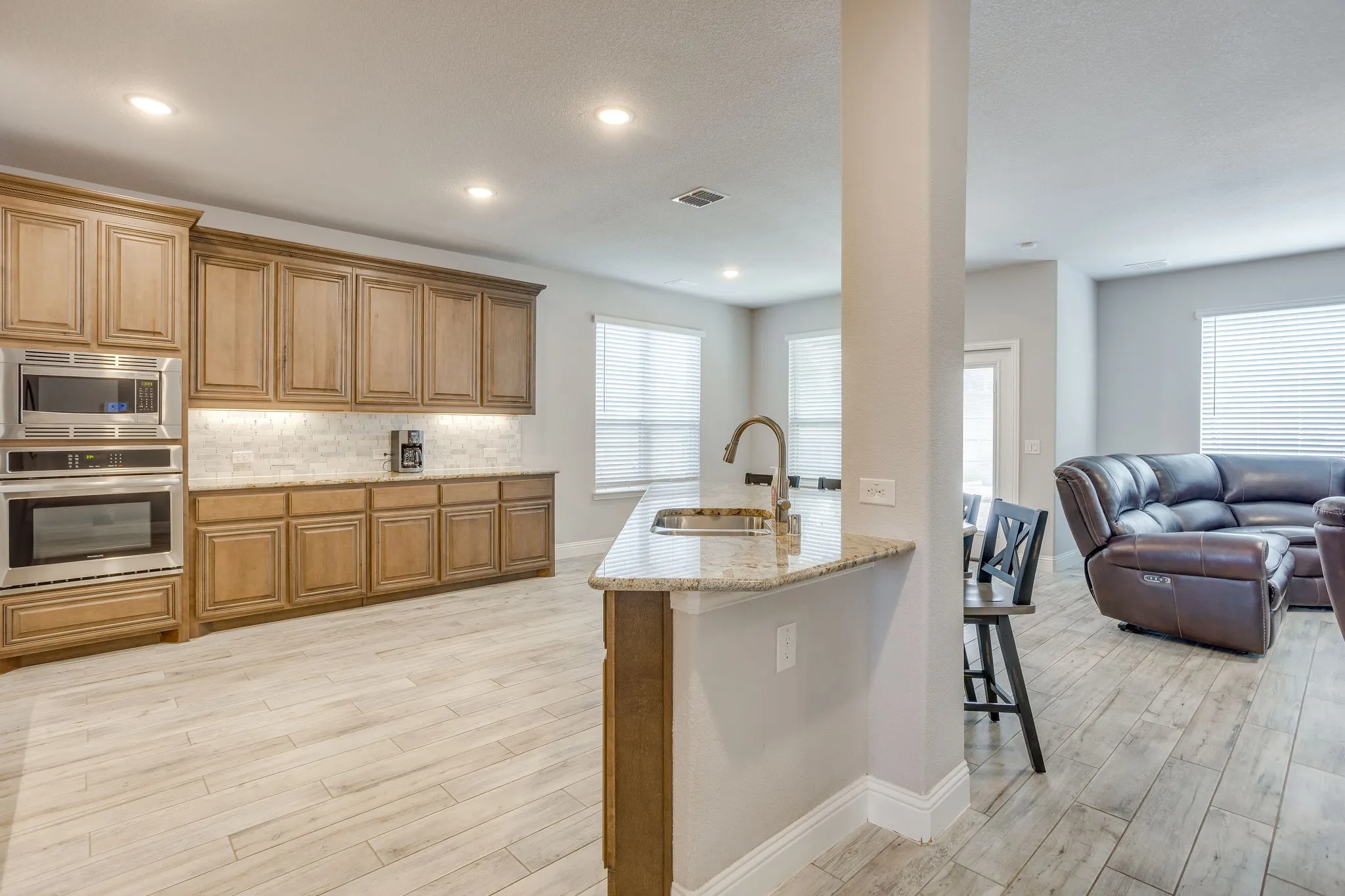 Spacious kitchen featuring extensive cabinetry, stainless steel built-in appliances, and light-toned wood-finish flooring