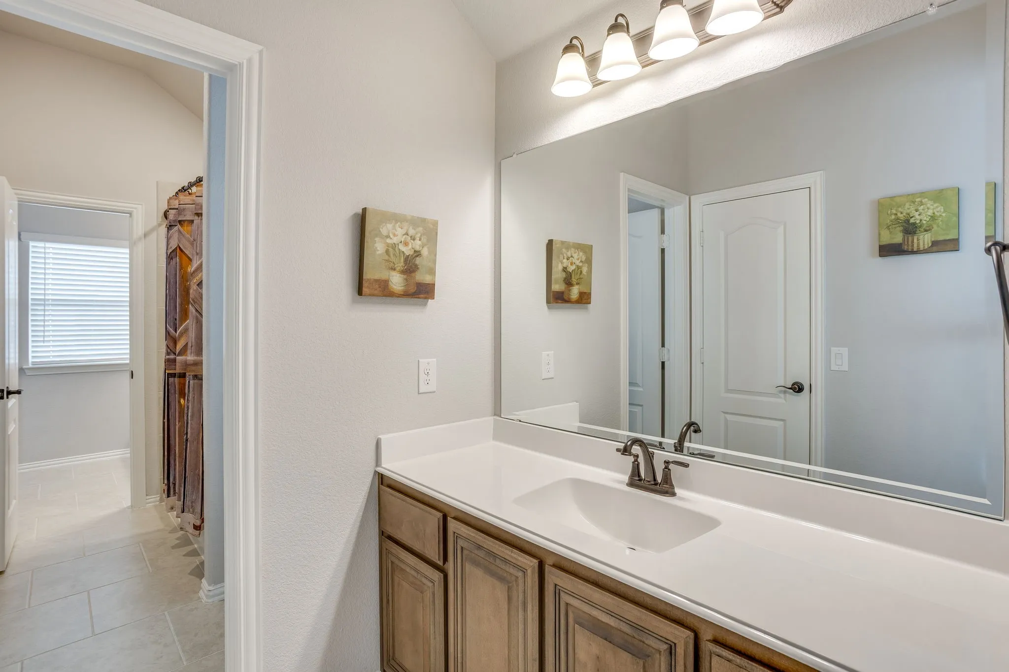 Vanity with a white countertop and integrated sink, featuring a bronze-finish faucet