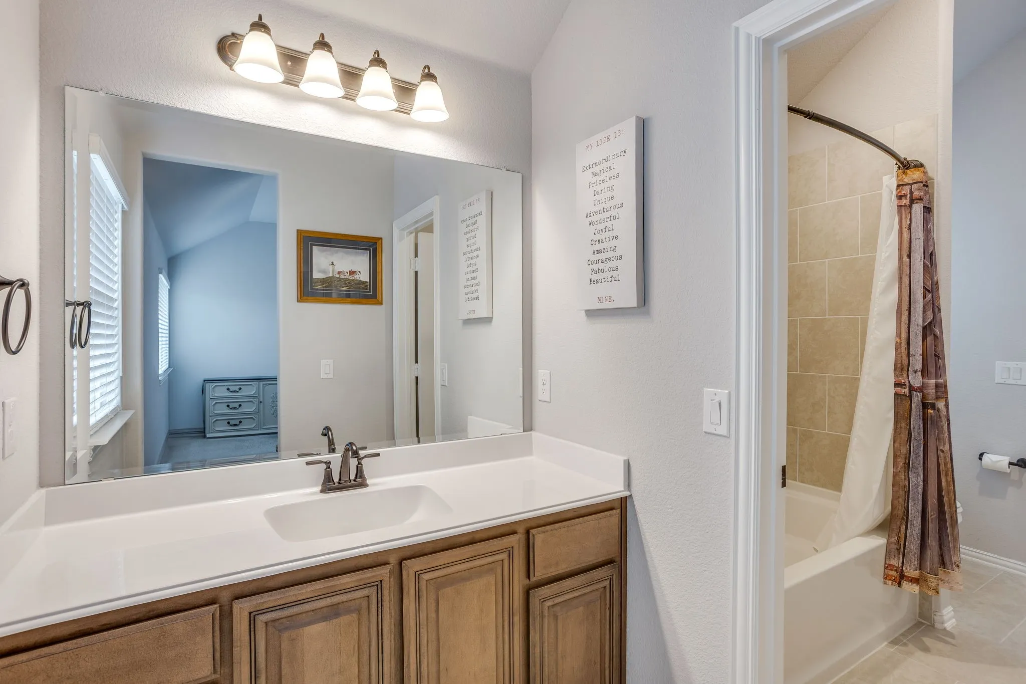 Bathroom vanity featuring a single basin sink, white countertop, and wood-finish cabinetry