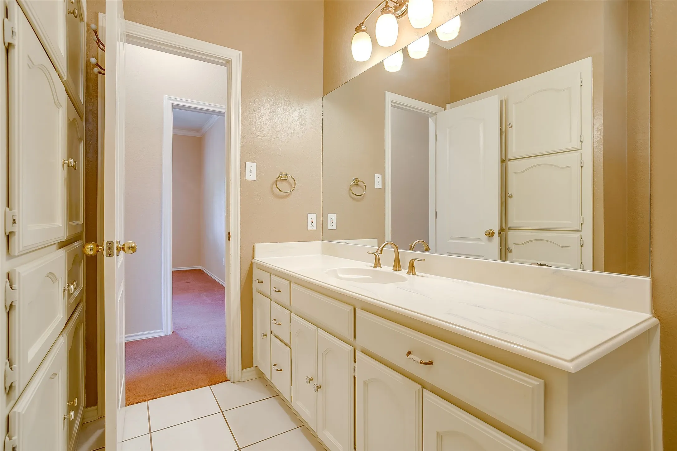 Bathroom vanity featuring a single sink, gold-tone hardware, and an expansive countertop