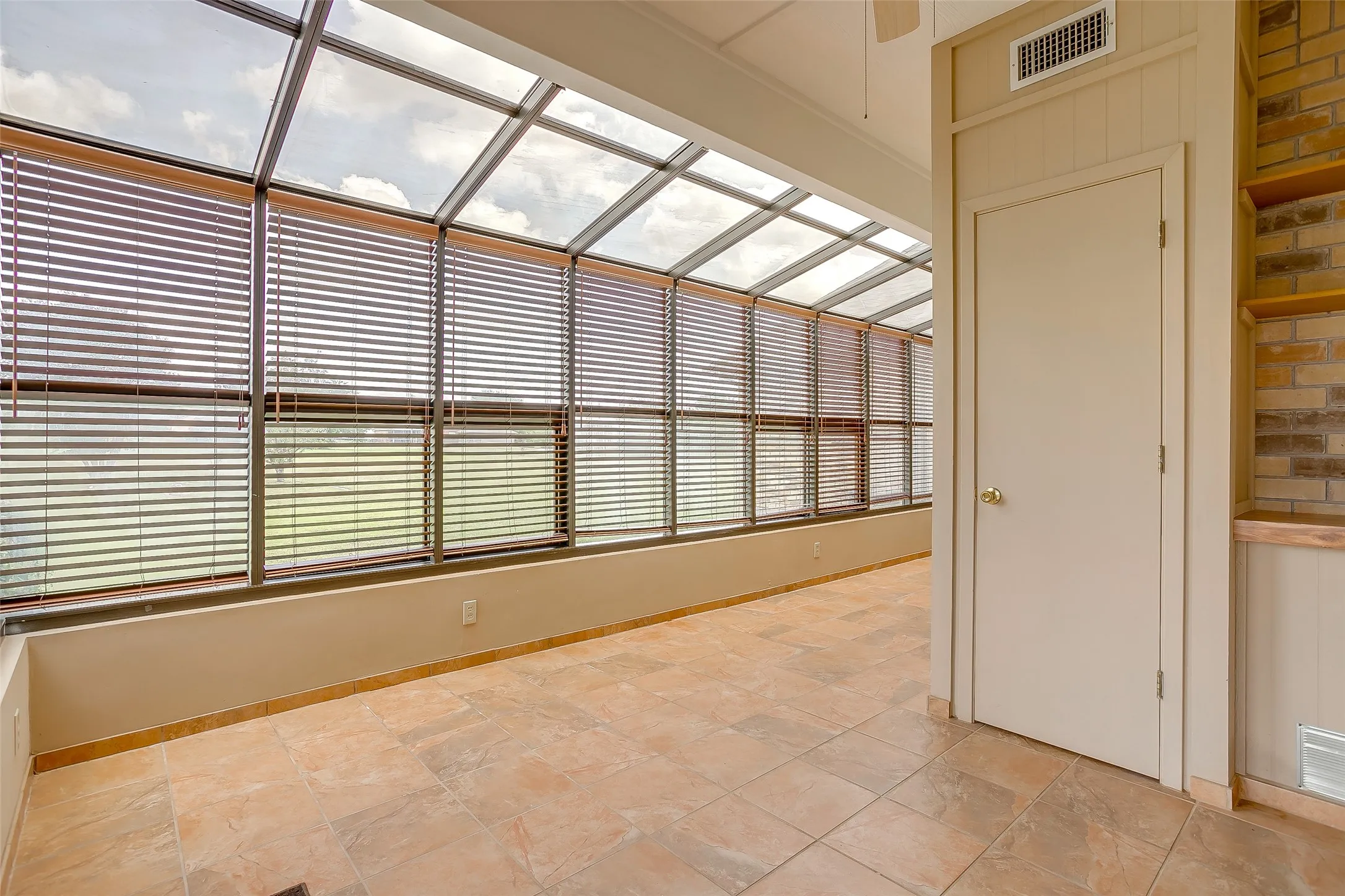 Sunroom featuring full-height windows with horizontal blinds and a sloped glass roof