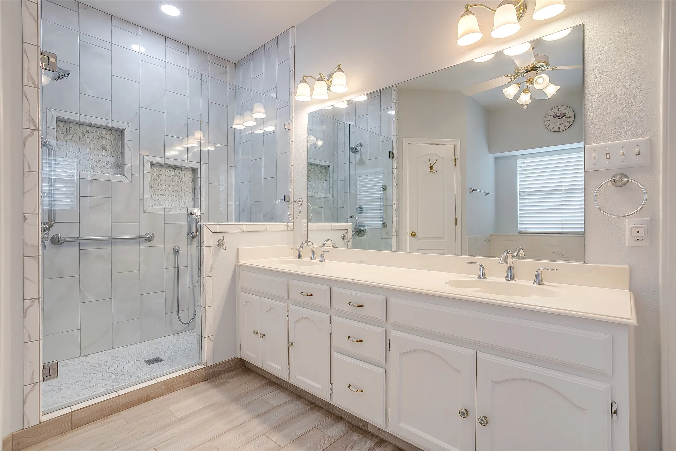 Bathroom featuring a dual vanity with white cabinetry, light-toned countertop, and chrome fixtures