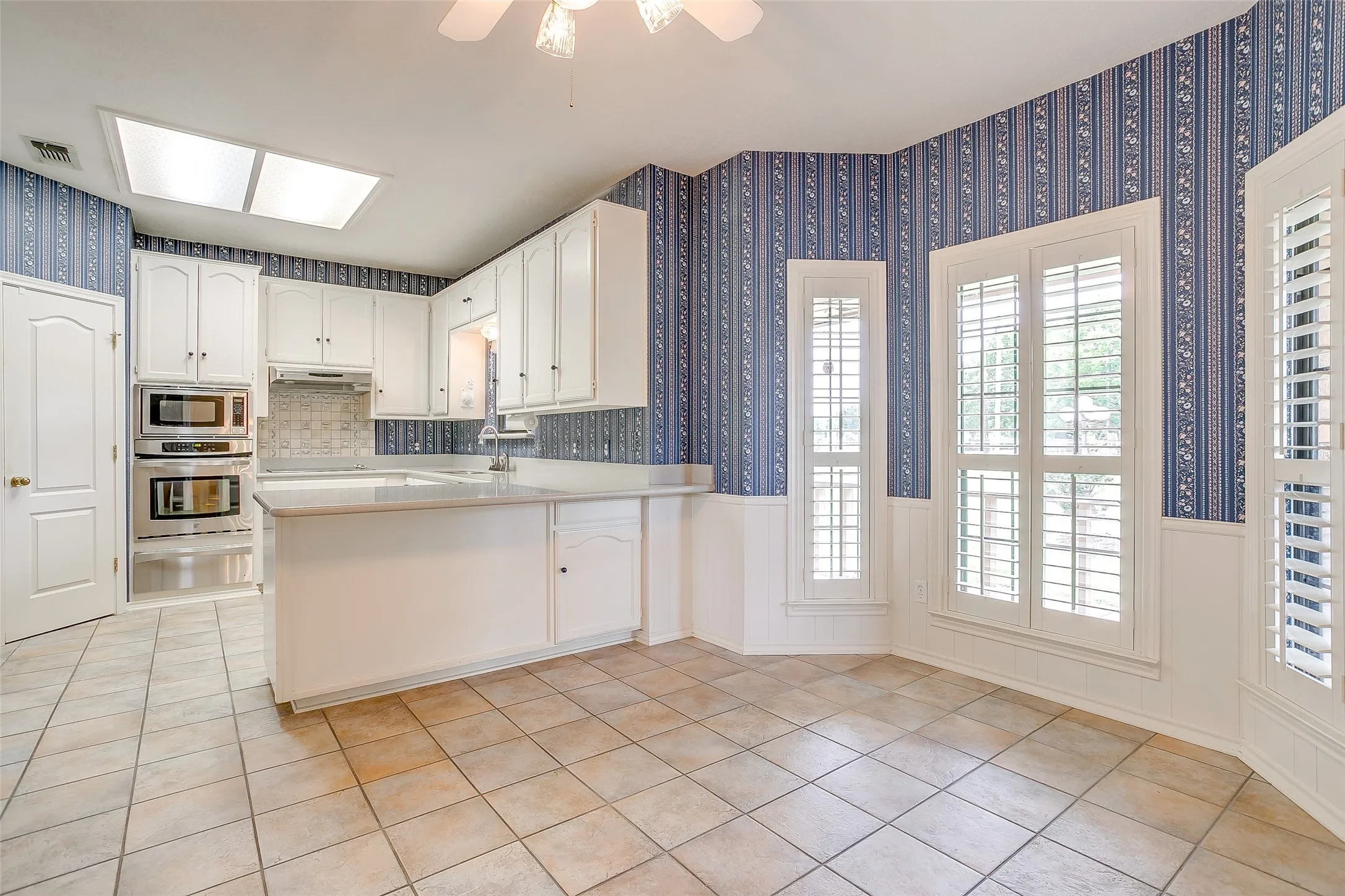 Kitchen featuring white cabinetry, light-toned countertops, built-in stainless steel appliances, and a tiled backsplash