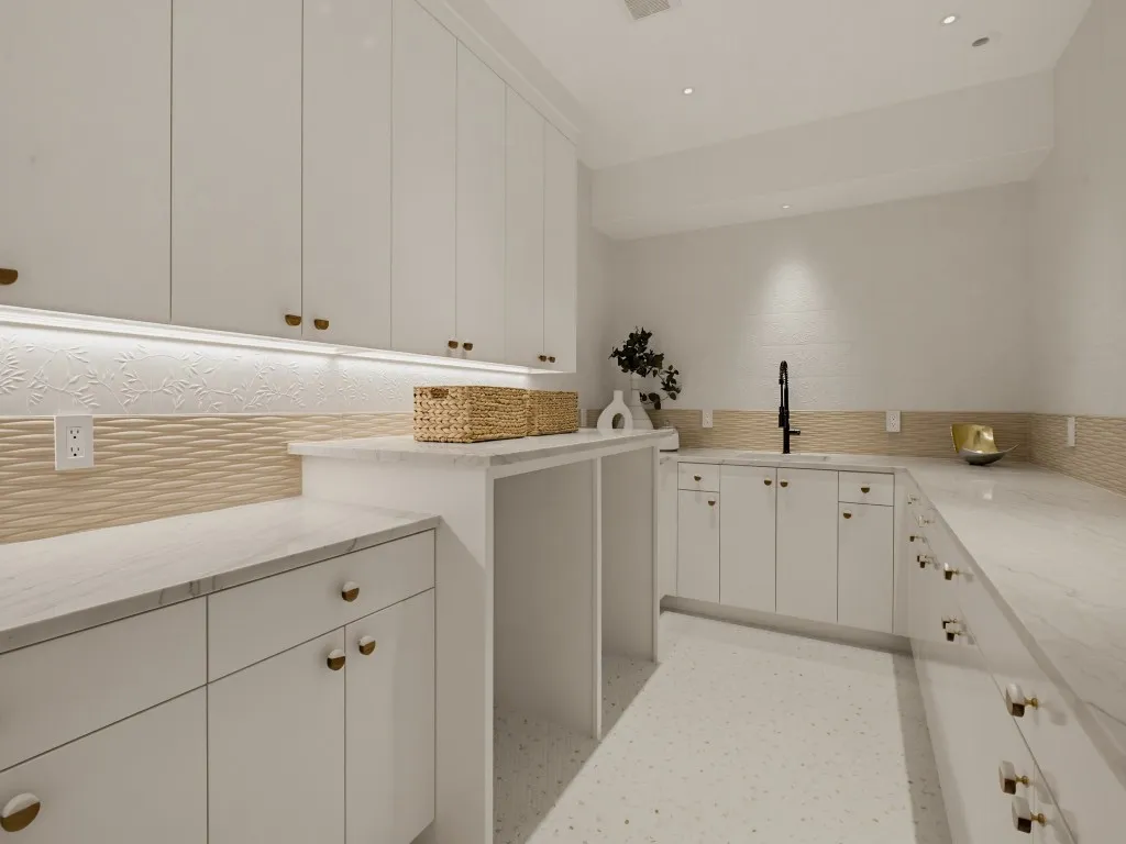 Spacious utility room featuring extensive white cabinetry, light-toned countertops, and a built-in sink with a matte black faucet
