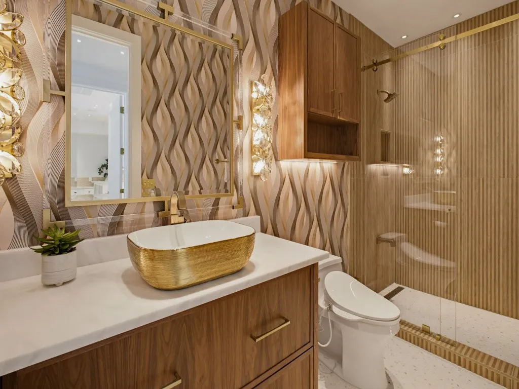 Bathroom featuring a gold vessel sink, wood-finish vanity with gold hardware, and a marble-look countertop