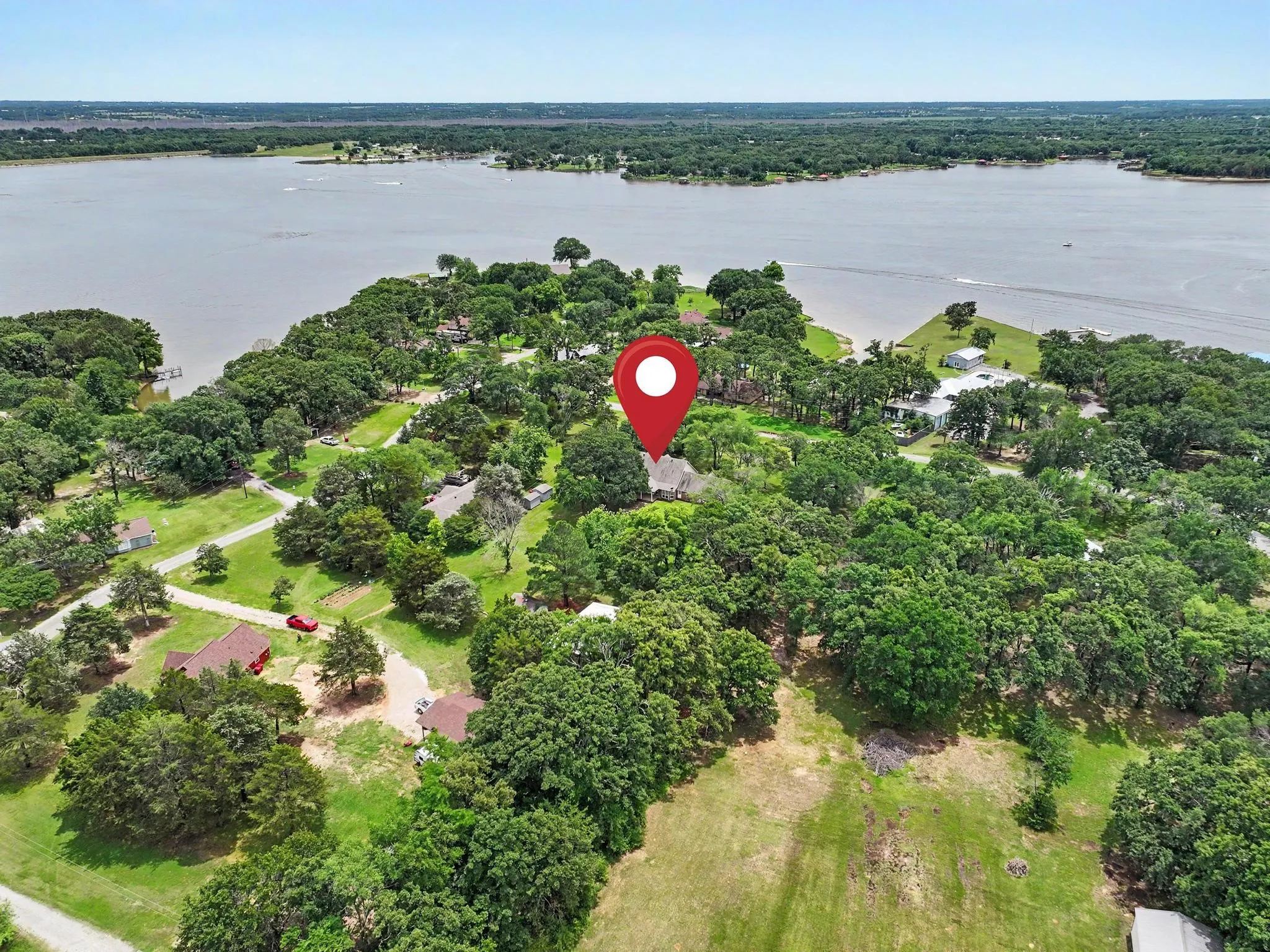 Aerial perspective showcasing waterfront proximity, surrounded by mature trees.