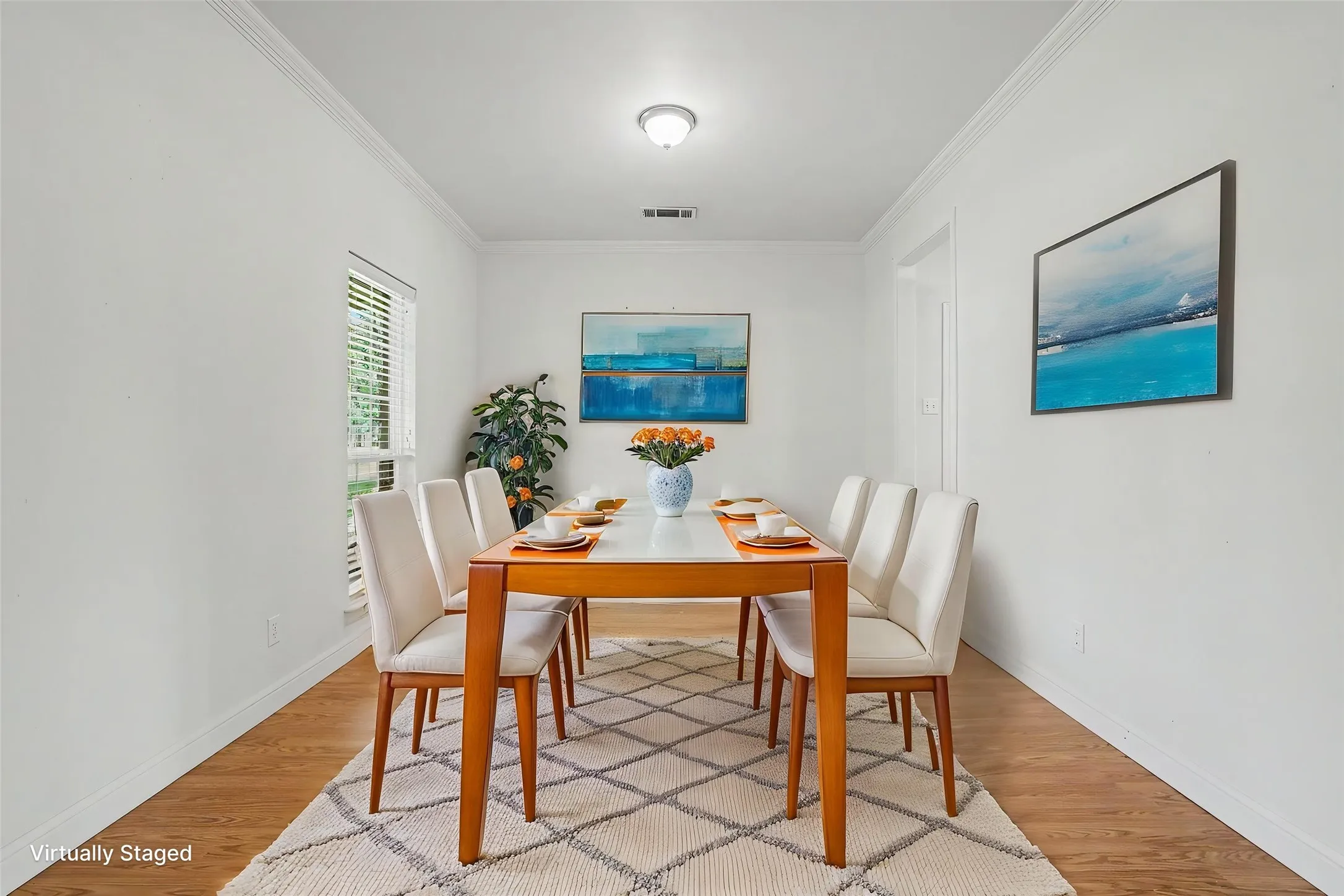 Dining area, which opens to the kitchen, features wood-finish flooring, white walls, and crown molding.
