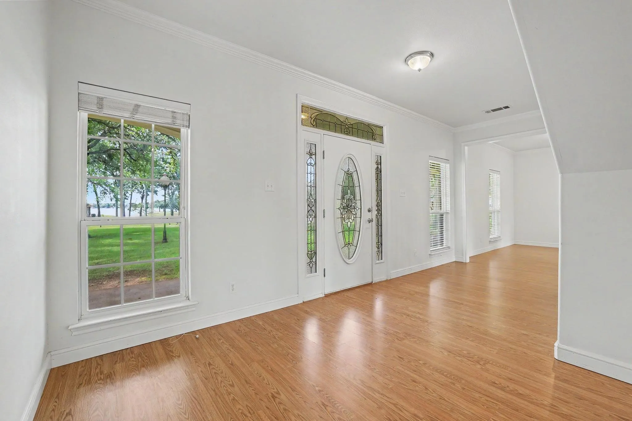 Foyer featuring wood-finish flooring, white walls, and a decorative glass entry door with sidelights.