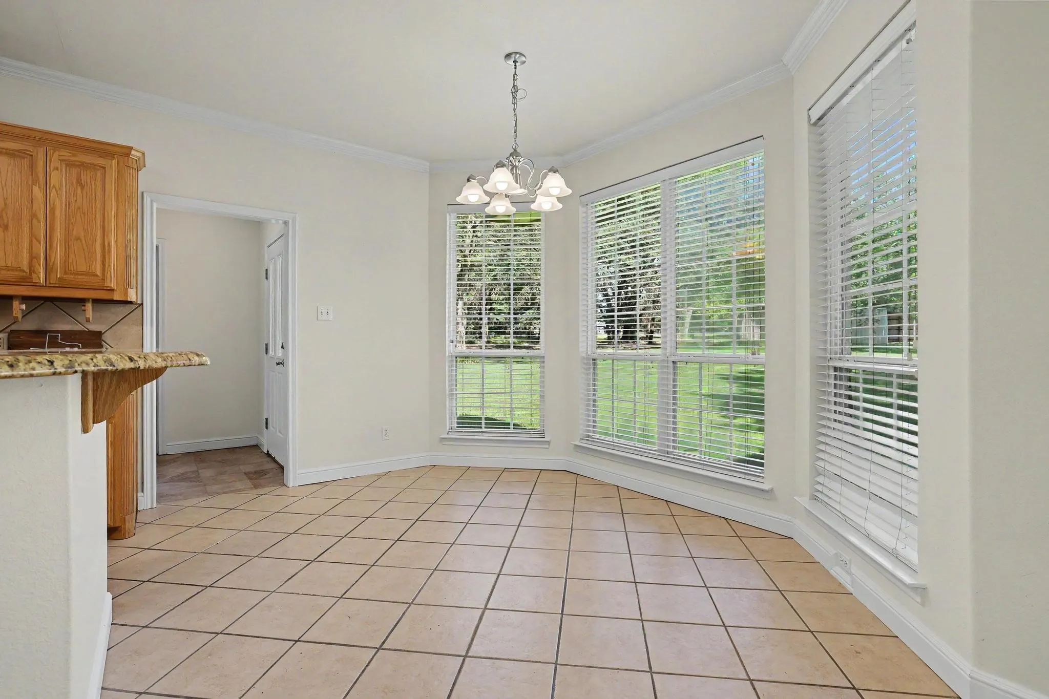 Bay window dining area featuring ceramic tile flooring, a chandelier, and a built-in breakfast bar with wood cabinetry and a stone-finish countertop