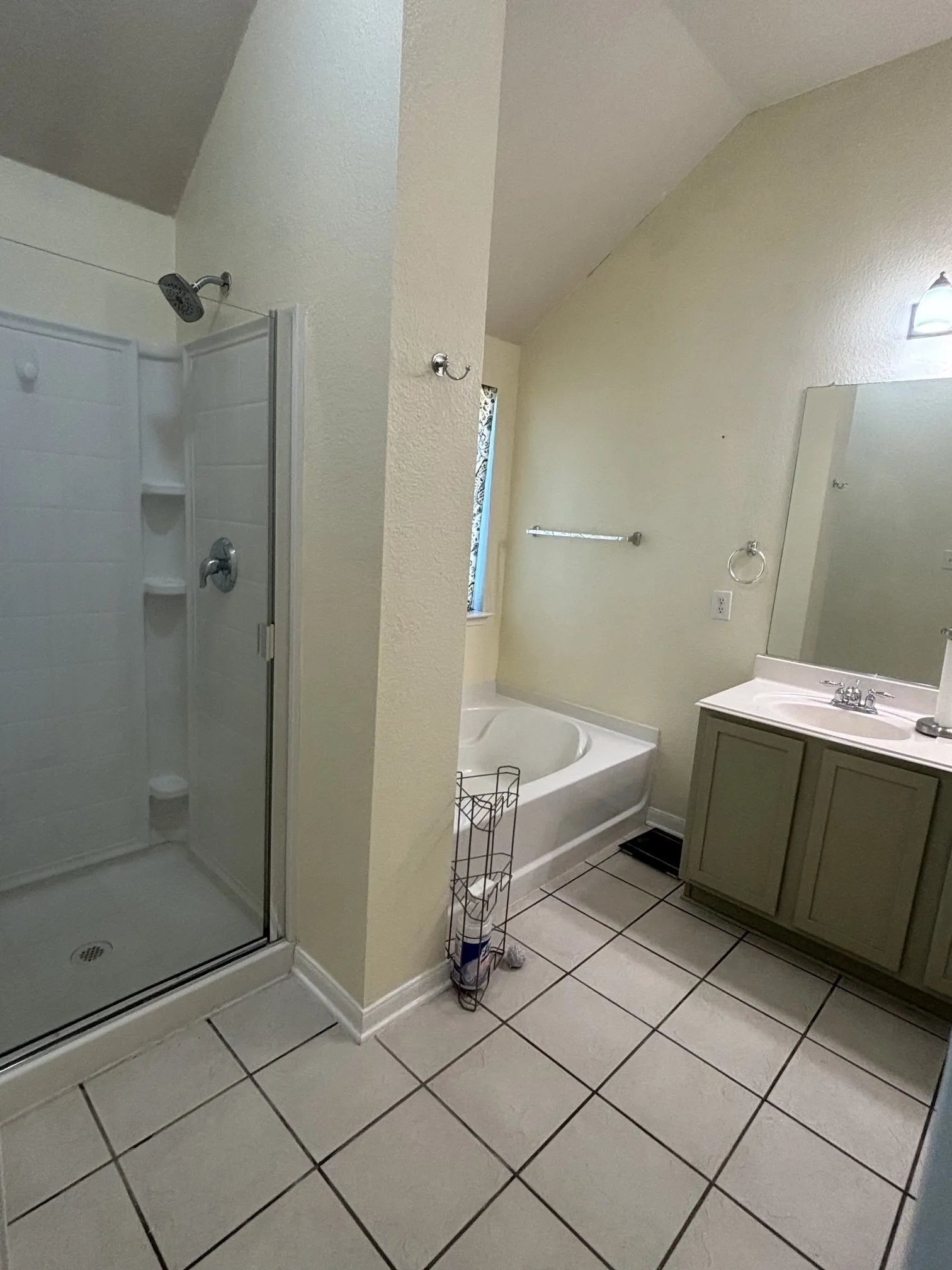 Bathroom featuring a glass-enclosed shower, a built-in tub, a single vanity with a white countertop and double-door cabinet, and tiled flooring