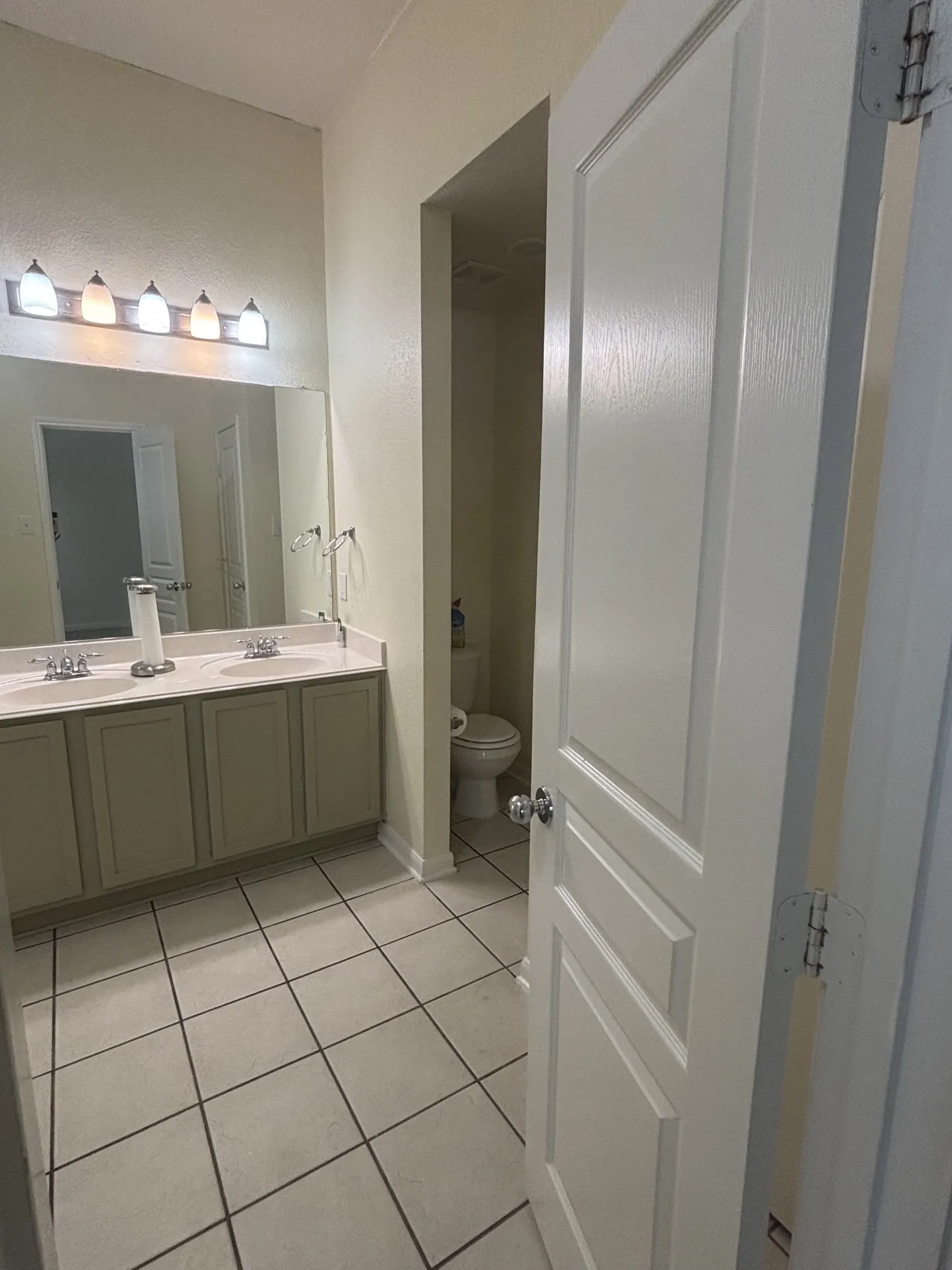 Double vanity with integrated sinks, light cabinetry, and a full-width mirror