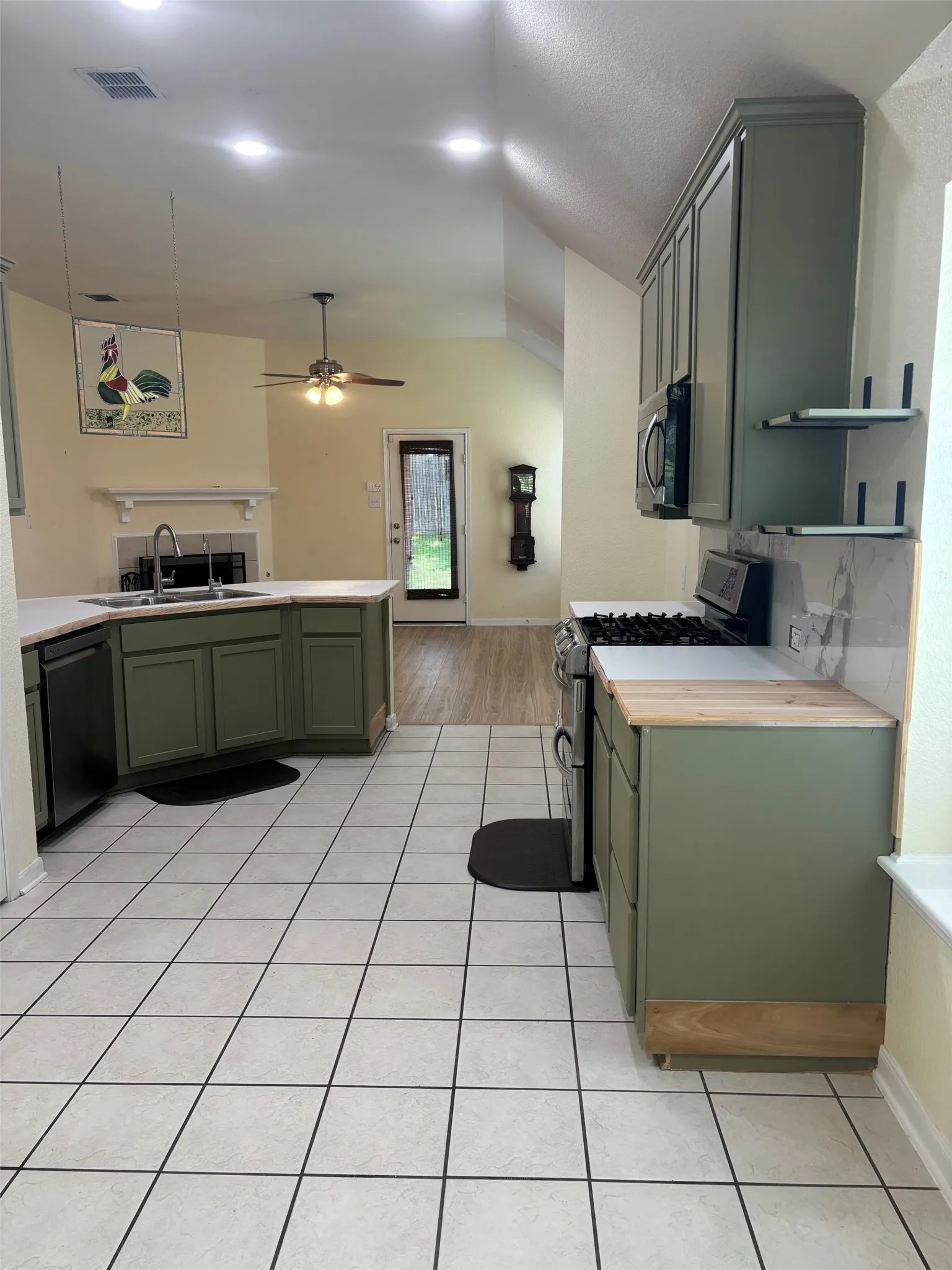 Kitchen featuring olive green cabinetry, white countertops, tile flooring, and a built-in range with microwave