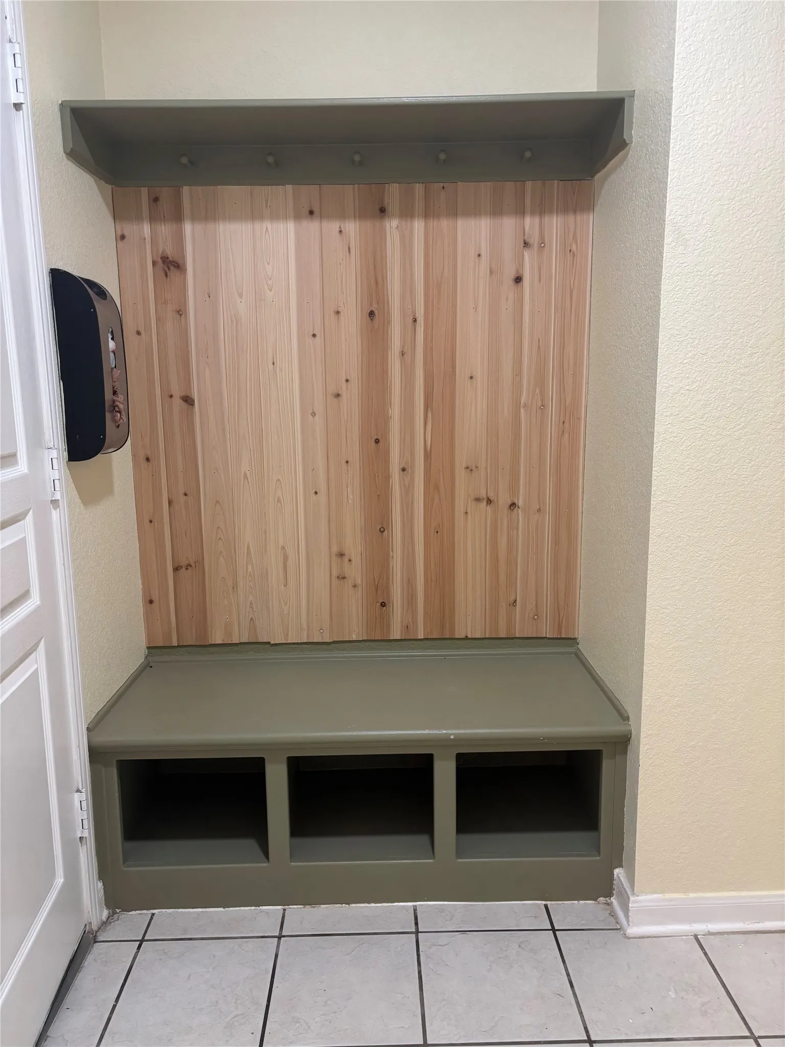 Built-in hall tree featuring natural wood paneling, a painted storage bench, and an upper shelf with integrated hooks