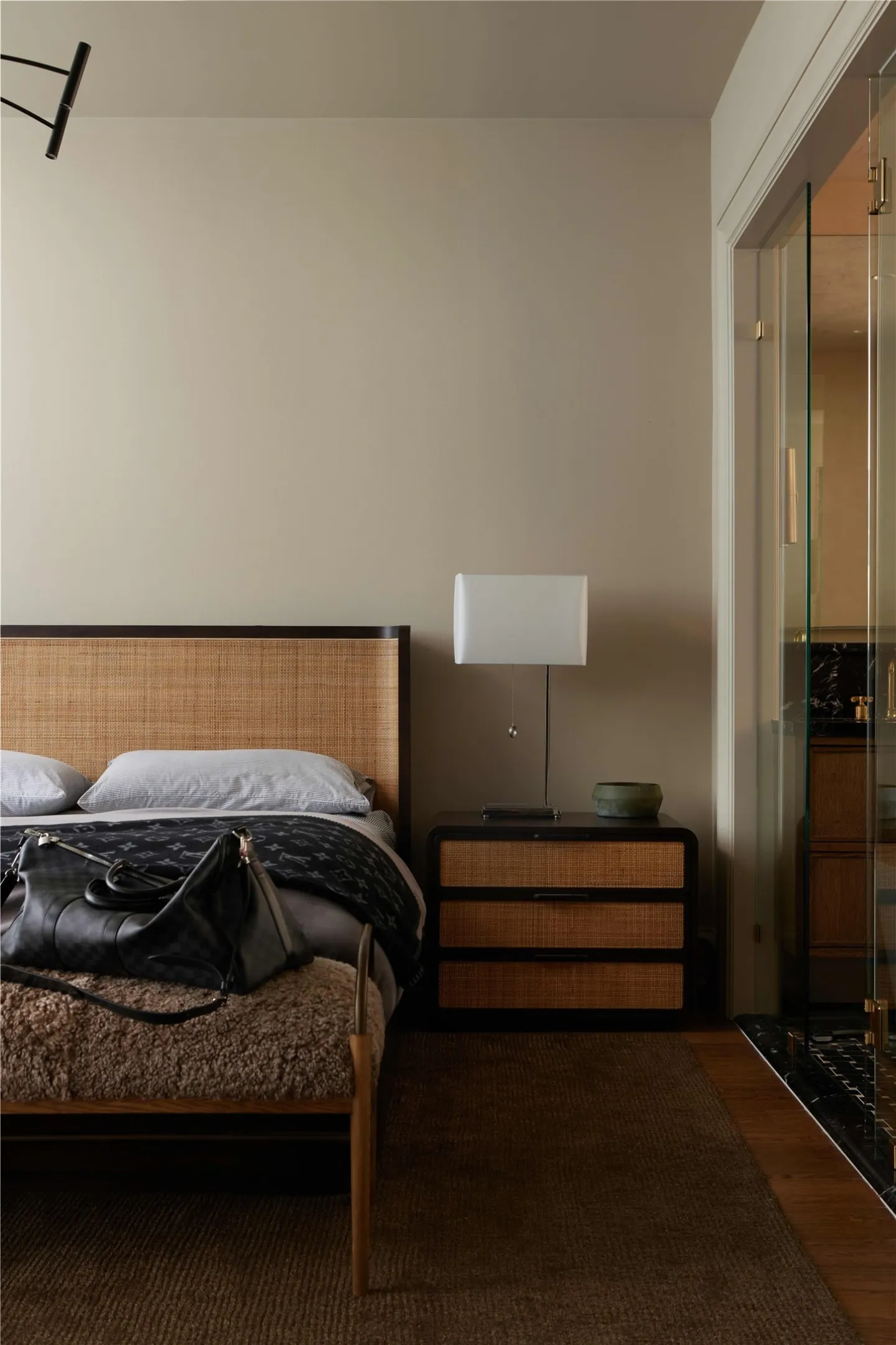 Bedroom featuring a woven headboard, wood-finish flooring, and a built-in glass shower enclosure