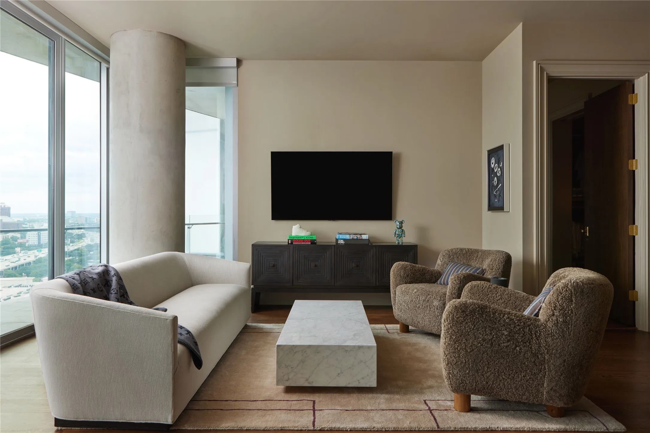 Spacious living area featuring floor-to-ceiling windows, dark wood-finish flooring, and light neutral wall tones