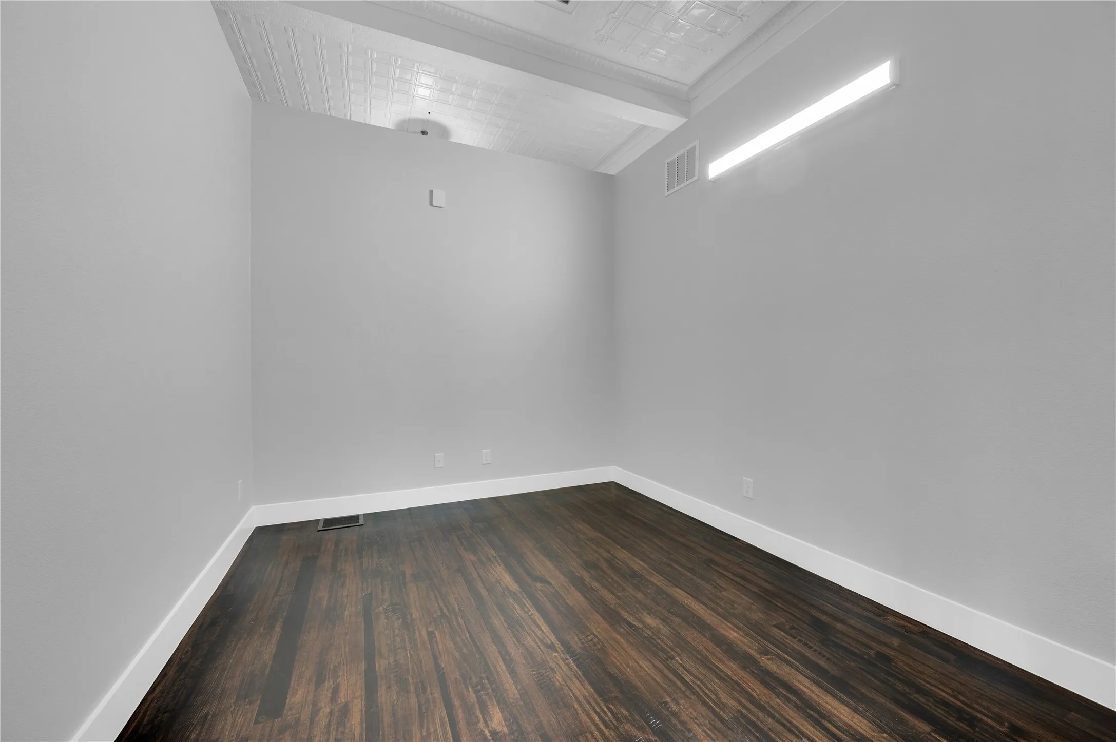 Room featuring dark wood-finish flooring, light grey walls, and white baseboards
