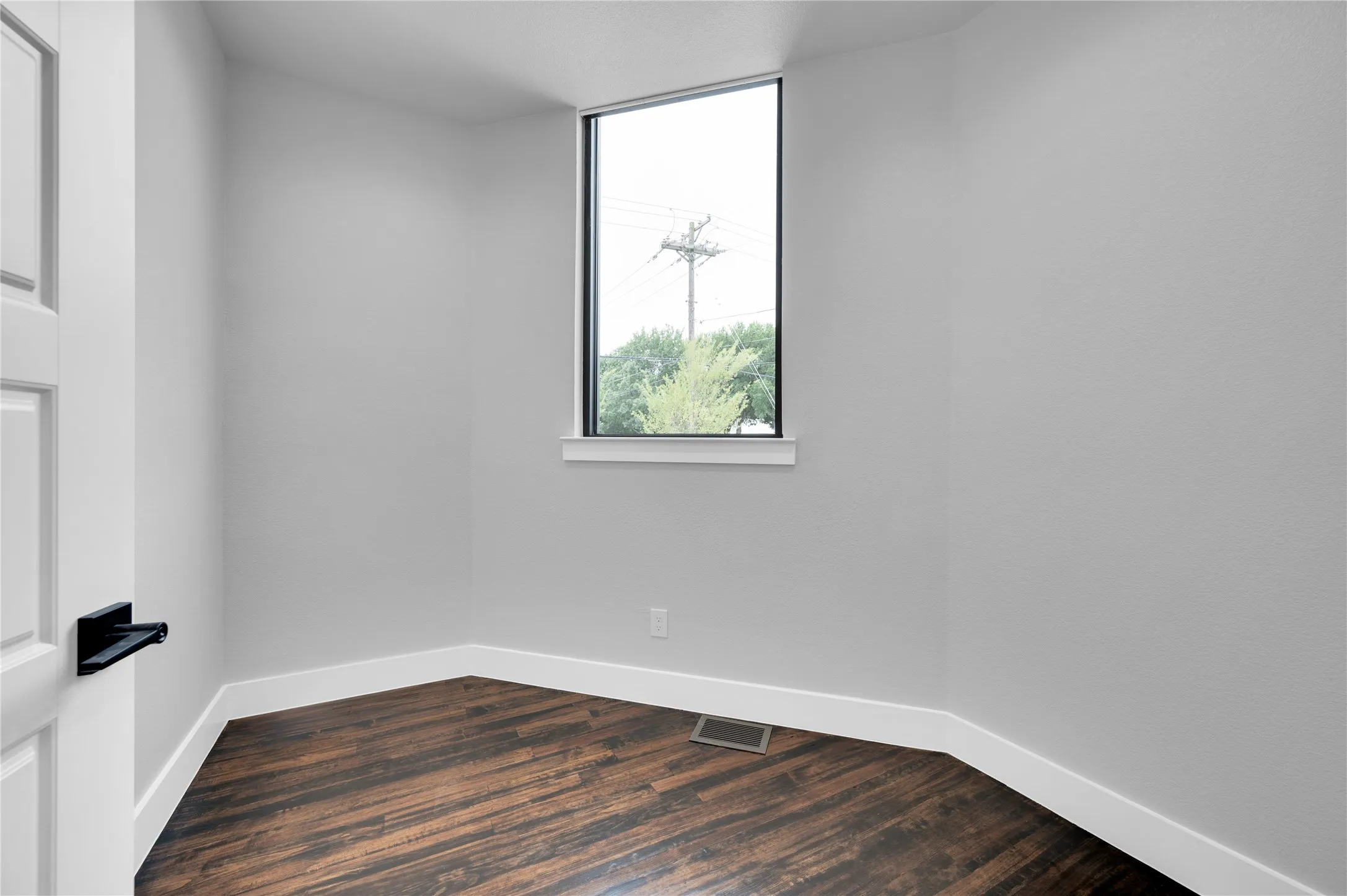 Room featuring wood-finish flooring, light grey walls, and white trim