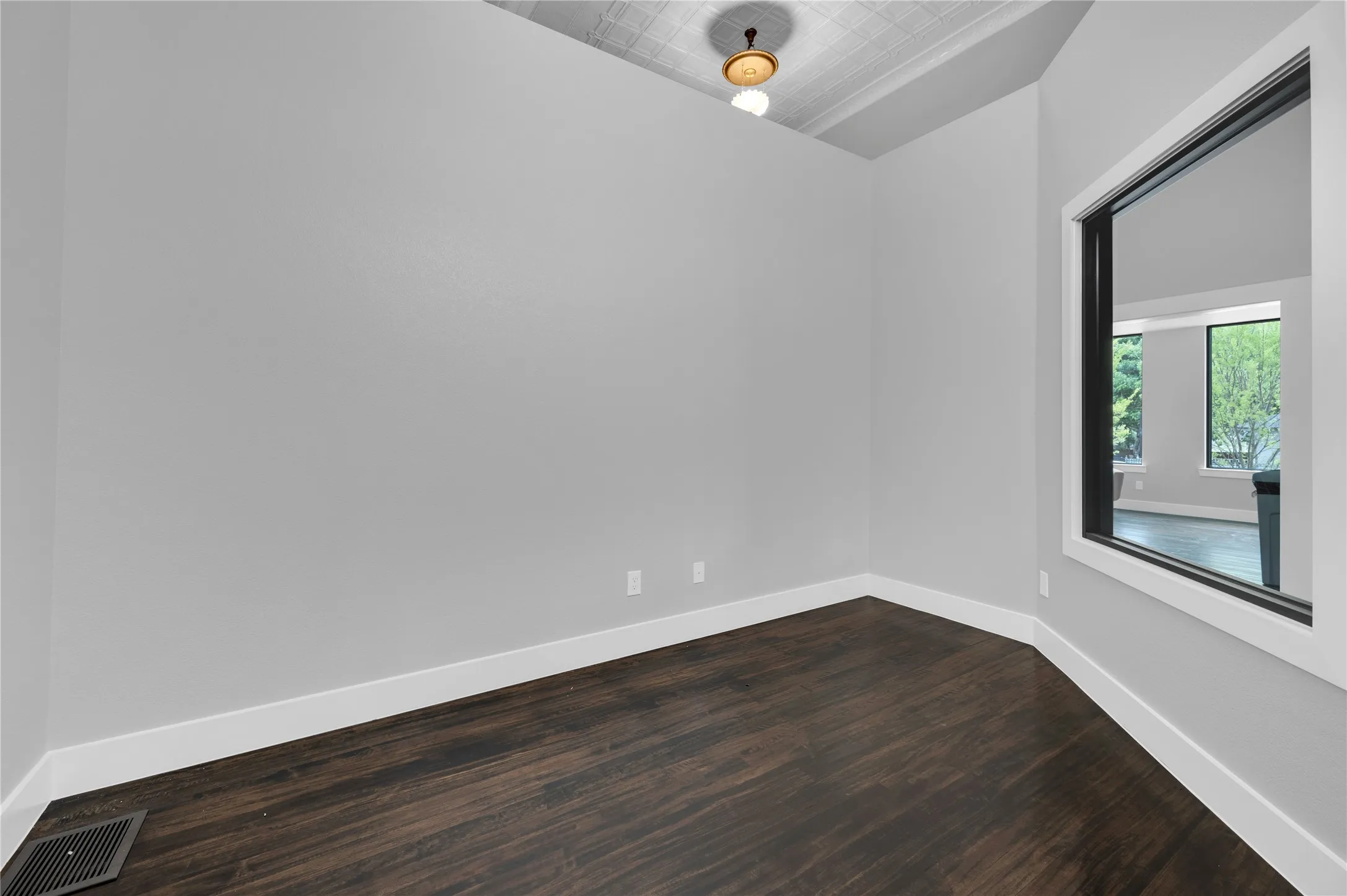 Interior room featuring dark wood-finish flooring, light gray walls, and white baseboards