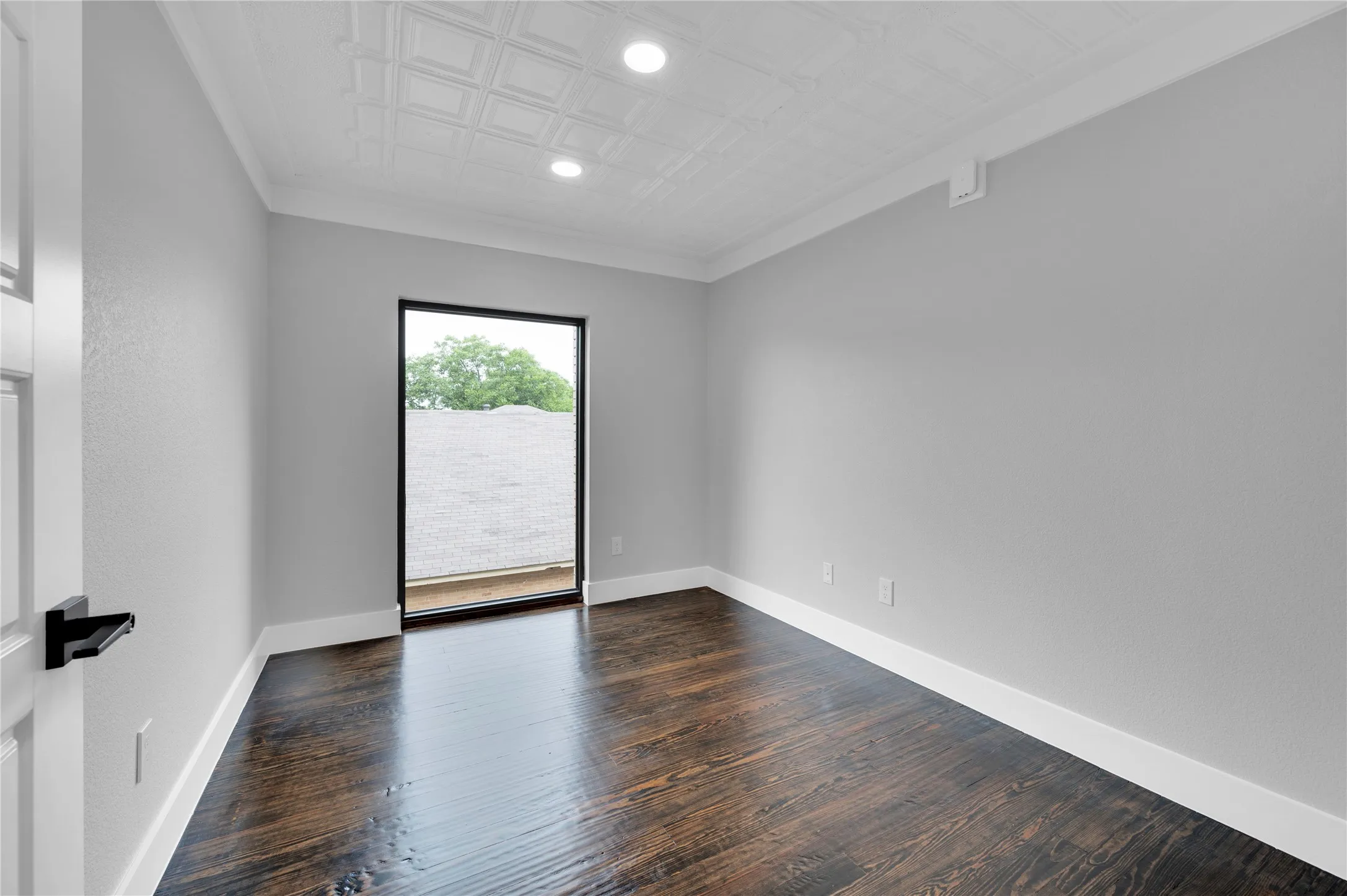 Interior room featuring dark wood-finish flooring, light gray walls, and white crown molding