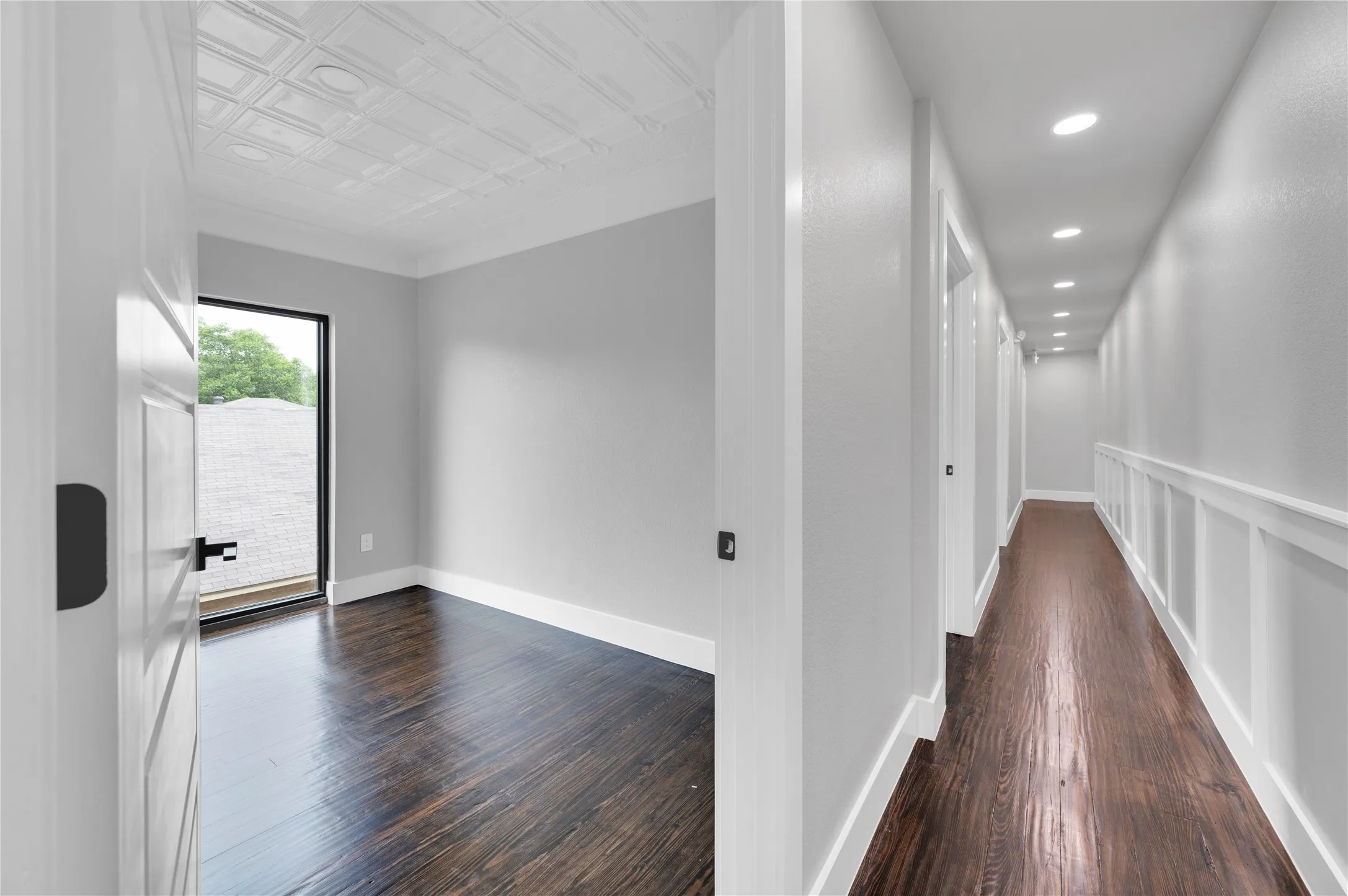 Wood-finish flooring throughout, featuring a hallway with recessed lighting and a paneled accent wall