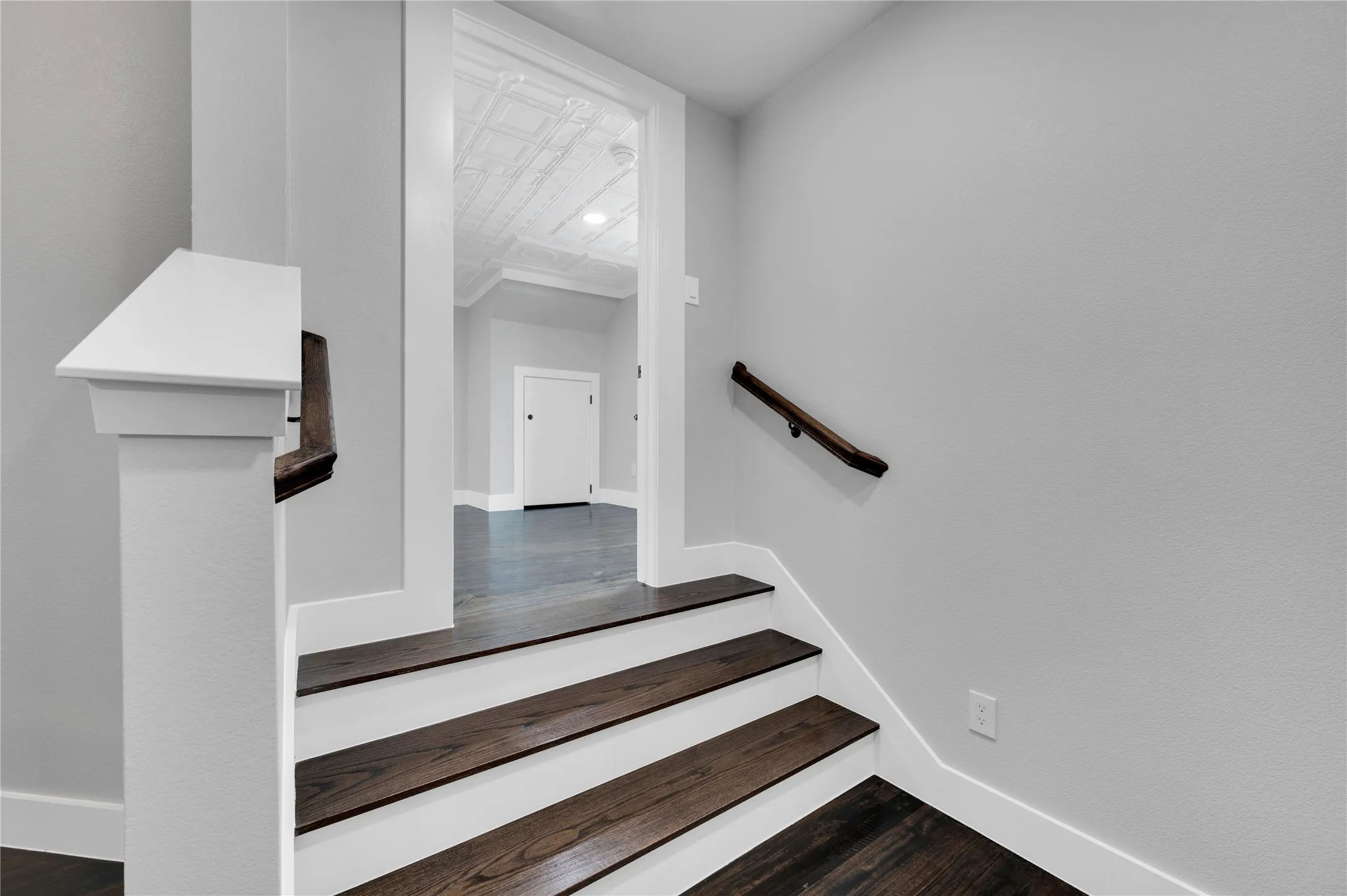Staircase featuring dark wood-finish treads and risers, a substantial white newel post, and a dark wood handrail