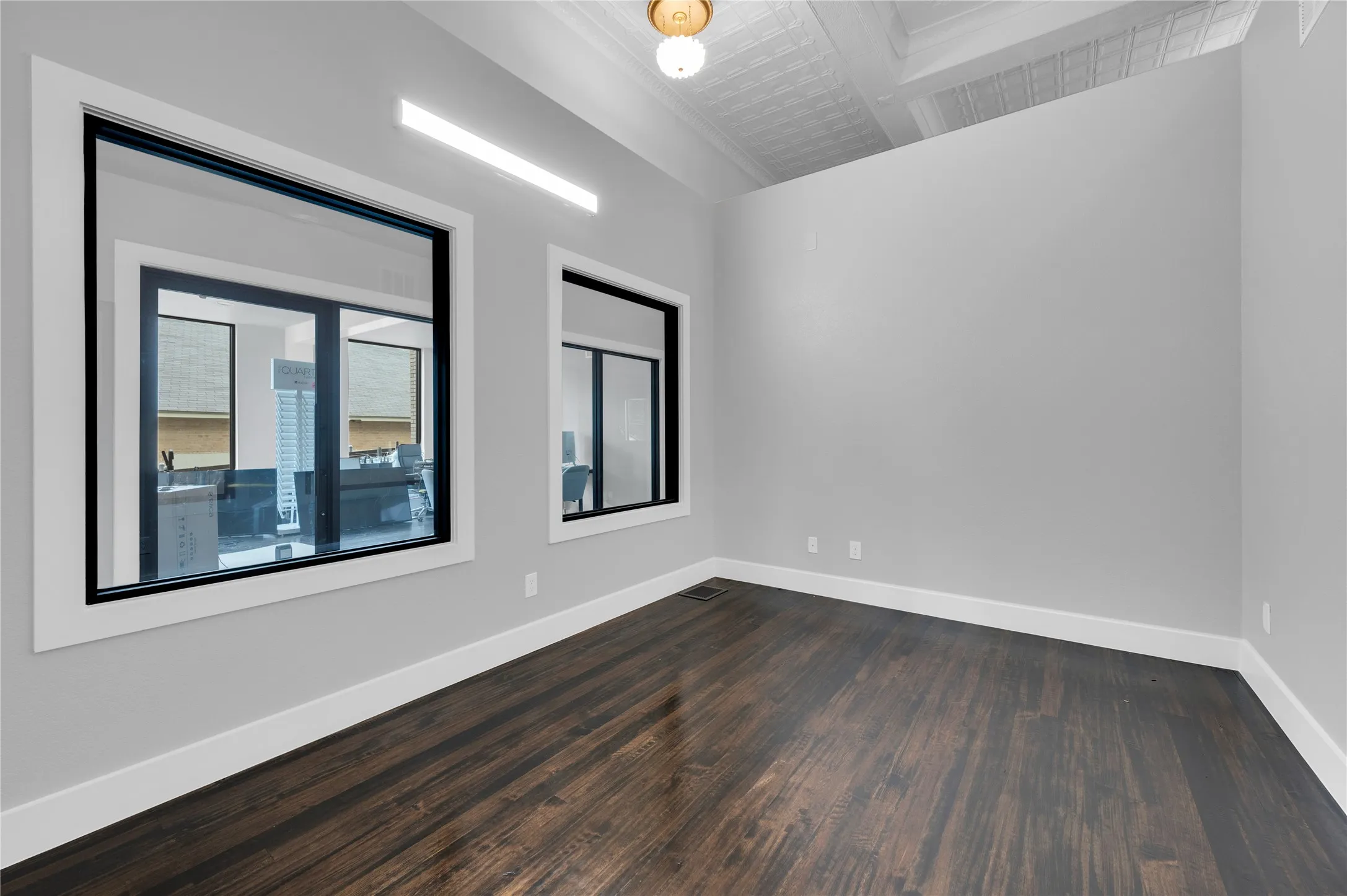 Spacious room featuring dark wood-finish flooring, light gray walls, and white baseboards