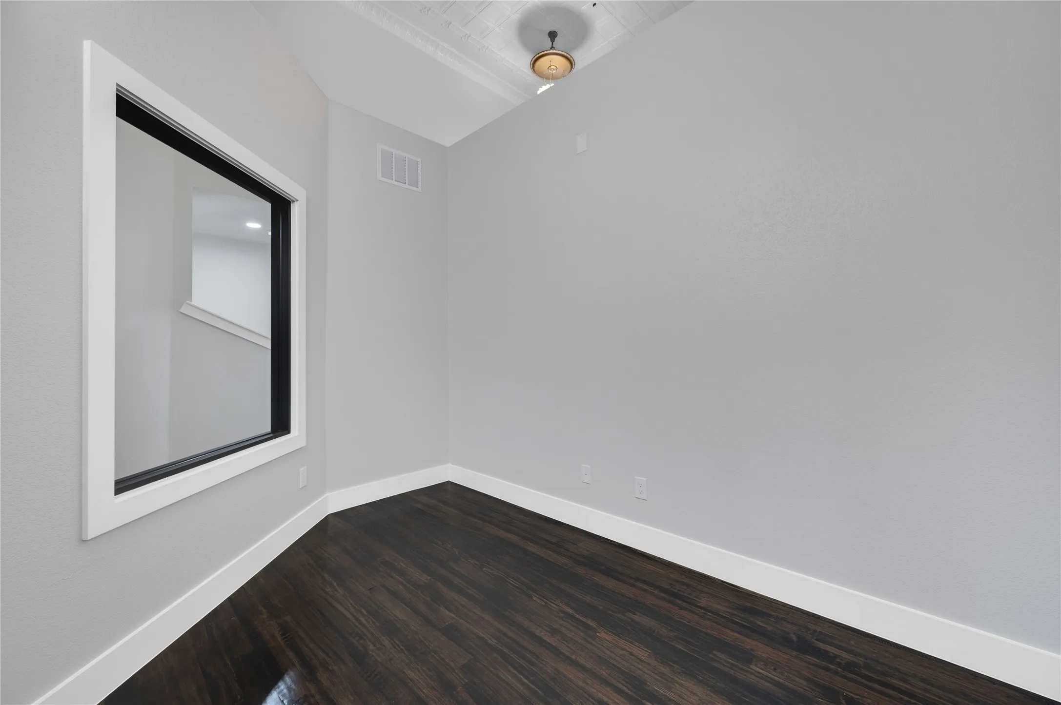 Room featuring dark wood-finish flooring, light grey walls, and white baseboards