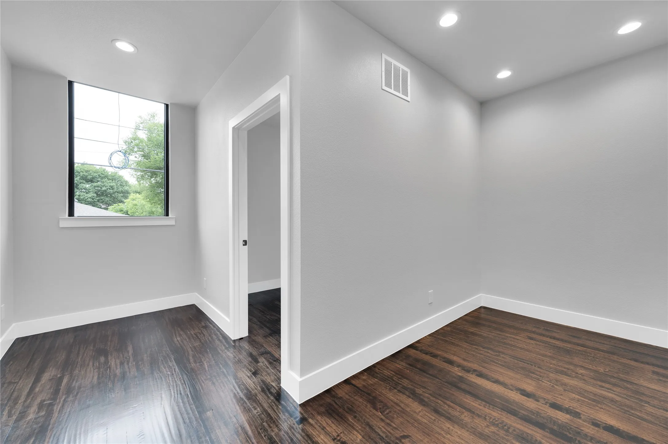 Room featuring wood-finish flooring, recessed lighting, and a large window