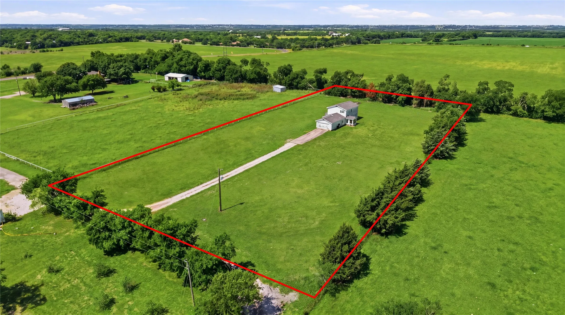 Aerial view highlighting the defined property boundaries of this massive green acreage, featuring a long private driveway and vast open spaces