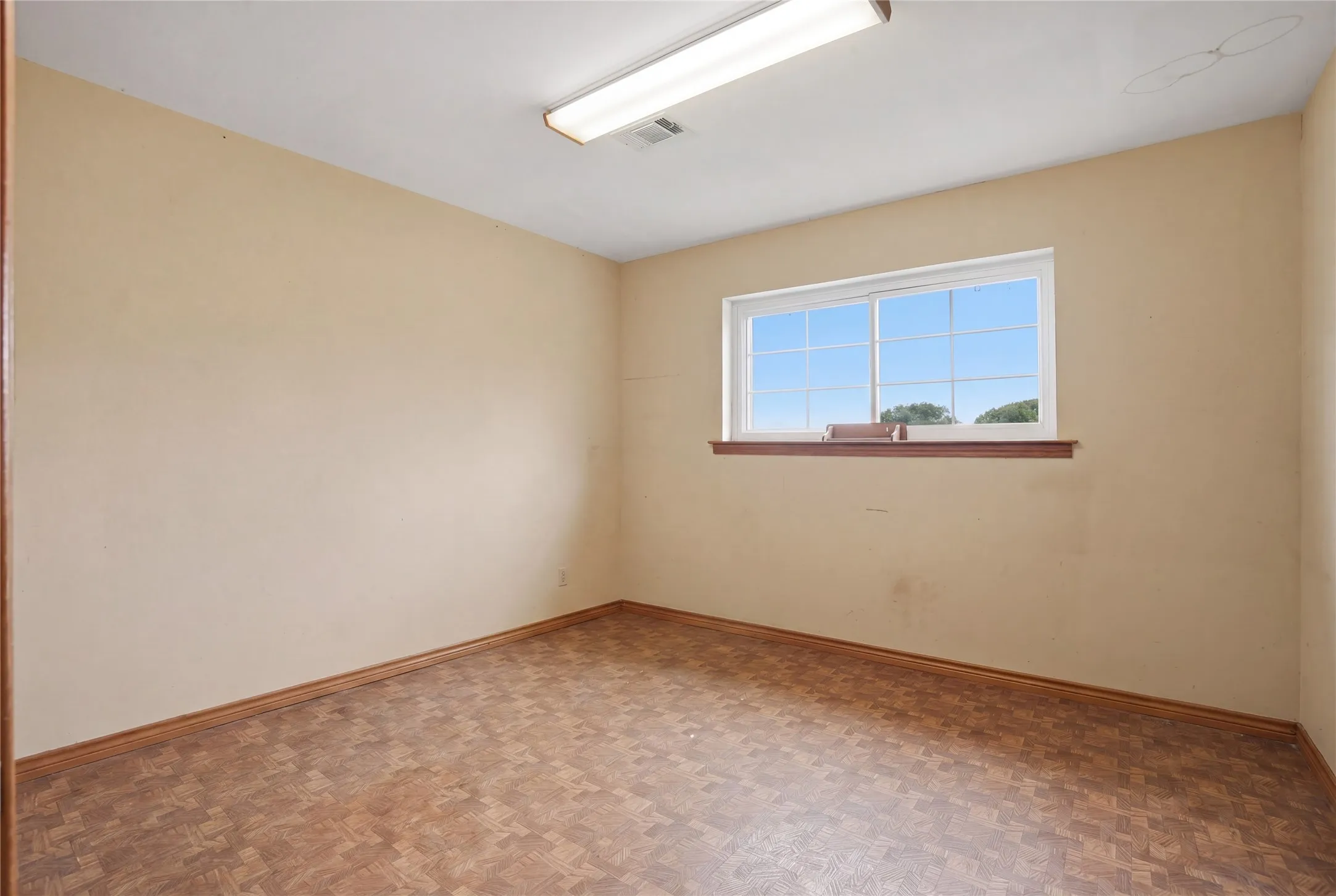 A wonderful blank canvas for a home office, study, or creative studio, complete with warm wood accents, durable flooring, and plenty of natural light