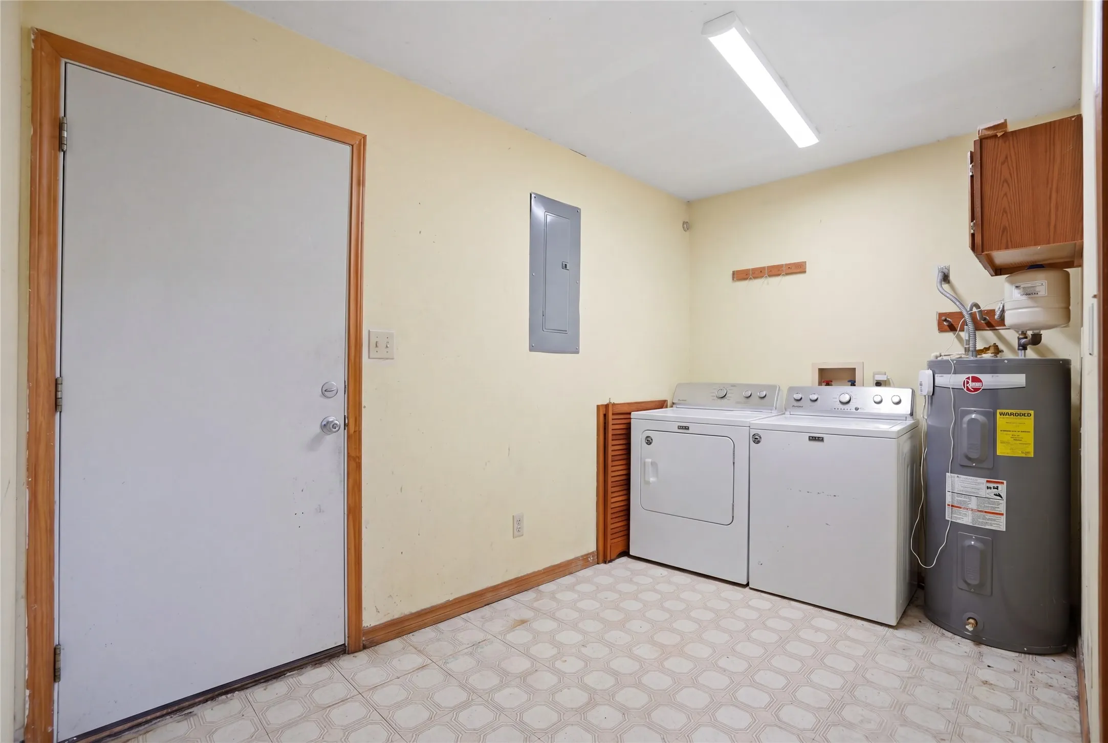 Utility space featuring a water heater, electrical panel, and vinyl flooring