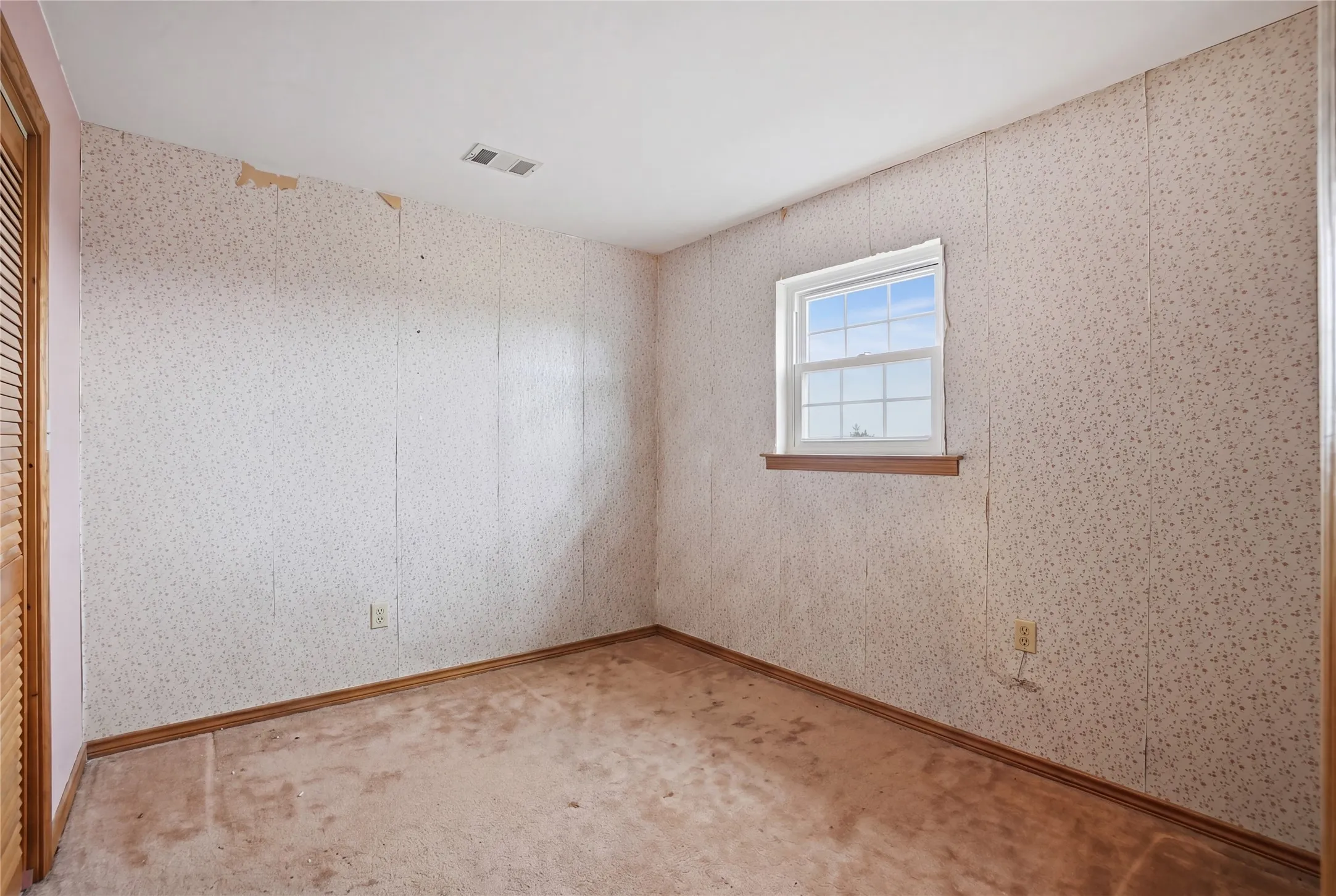 Sleeping space featuring warm trim details and an expansive window that fills the room with natural light