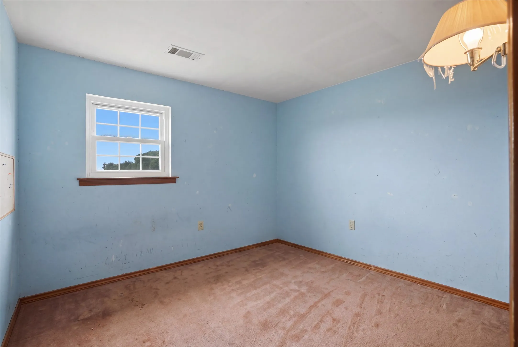 Cozy bedroom offering generous space for a full suite, complemented by warm wood trim and a large window