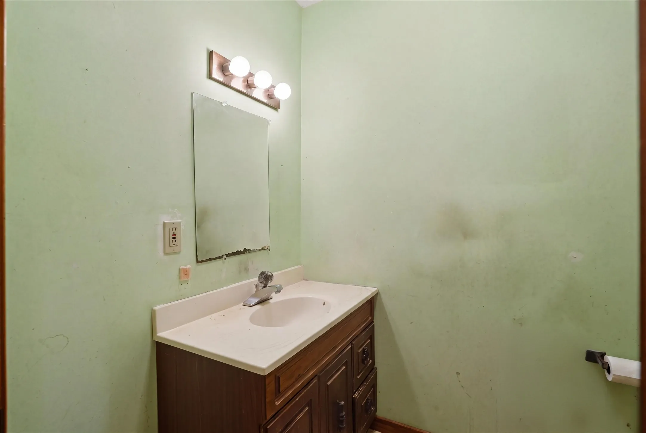Practical powder room offering a functional layout, complete with a dark wood vanity, integrated sink, and overhead lighting