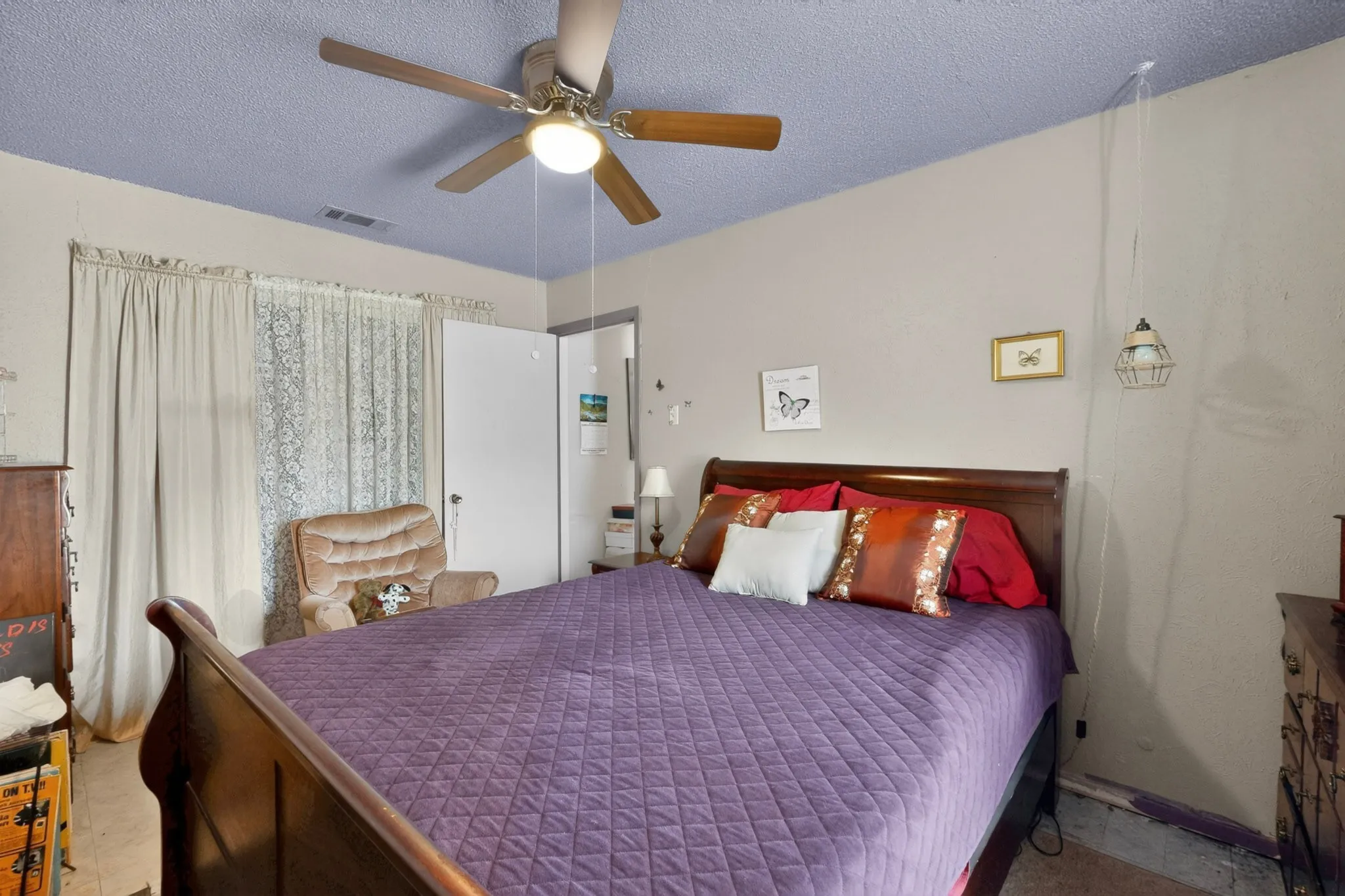 Bedroom featuring a ceiling fan with integrated lighting, textured blue ceiling, and a window with curtains