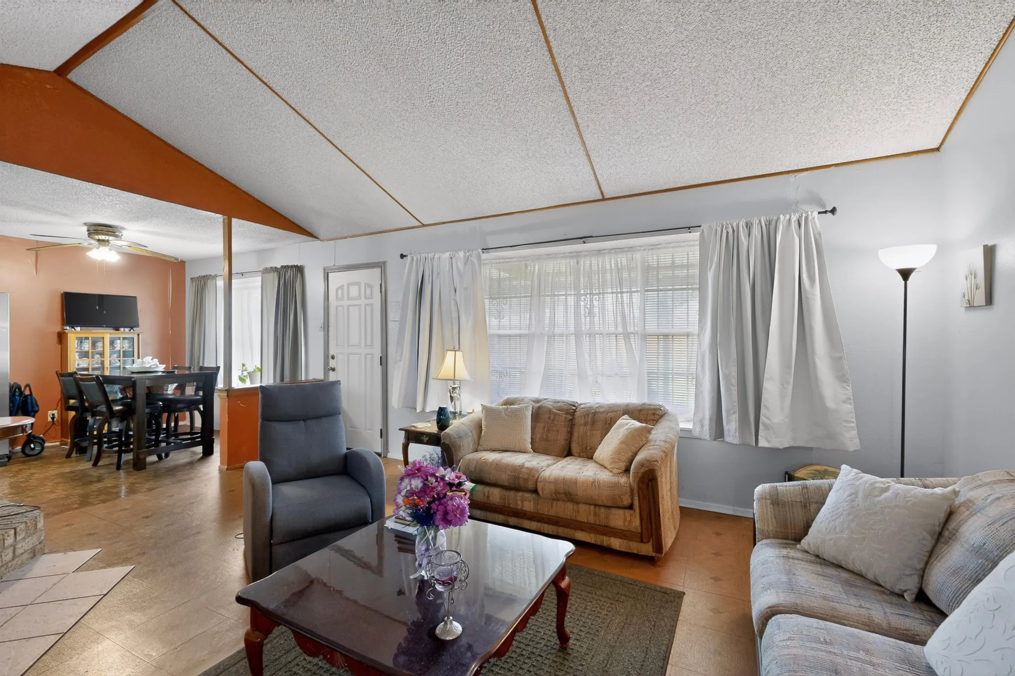 Open concept living area featuring vaulted ceilings, wood-finish flooring, and a dining area with a ceiling fan