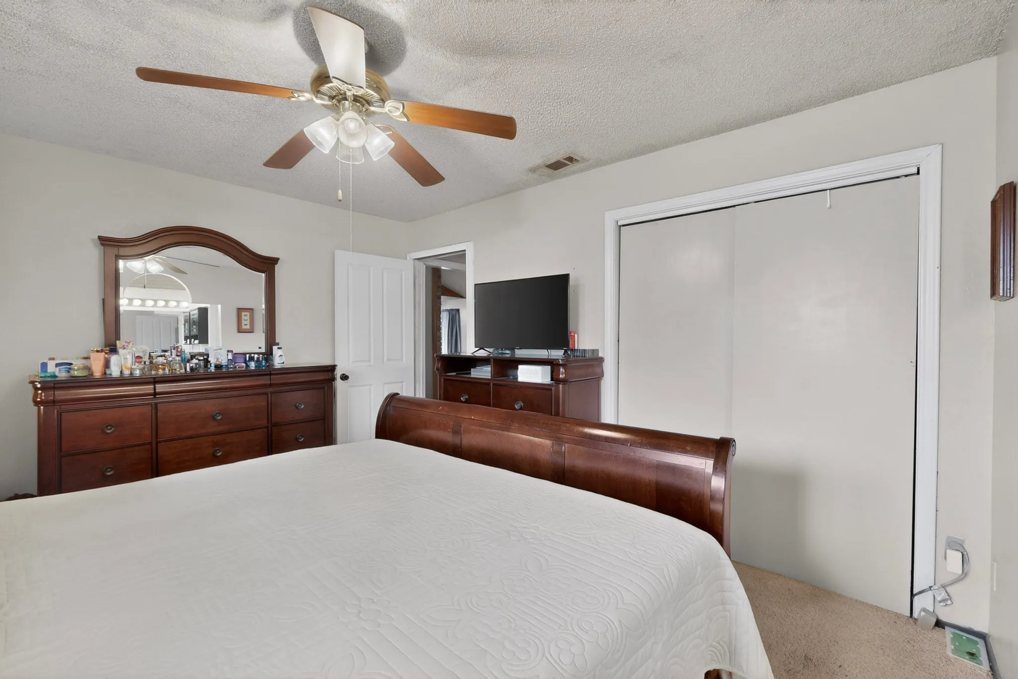 Carpeted room featuring a ceiling fan with light fixture and a closet with bi-fold doors