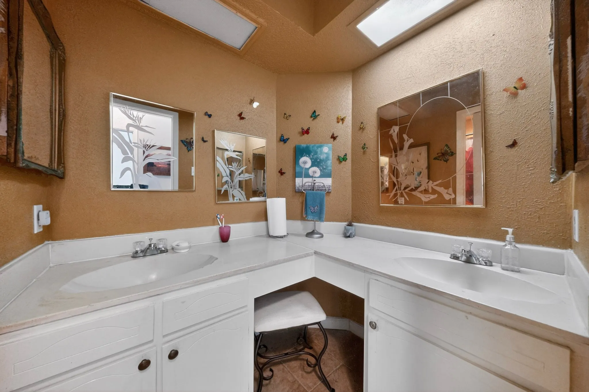 Dual vanity with white cabinetry and integrated sinks, under-counter knee space, and overhead skylight