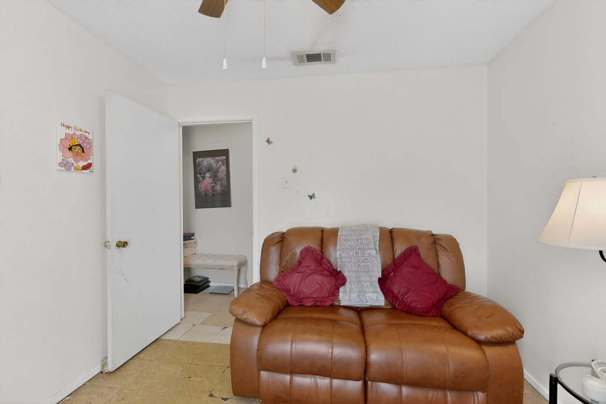 White painted walls with a textured ceiling, a ceiling fan, and light-toned flooring
