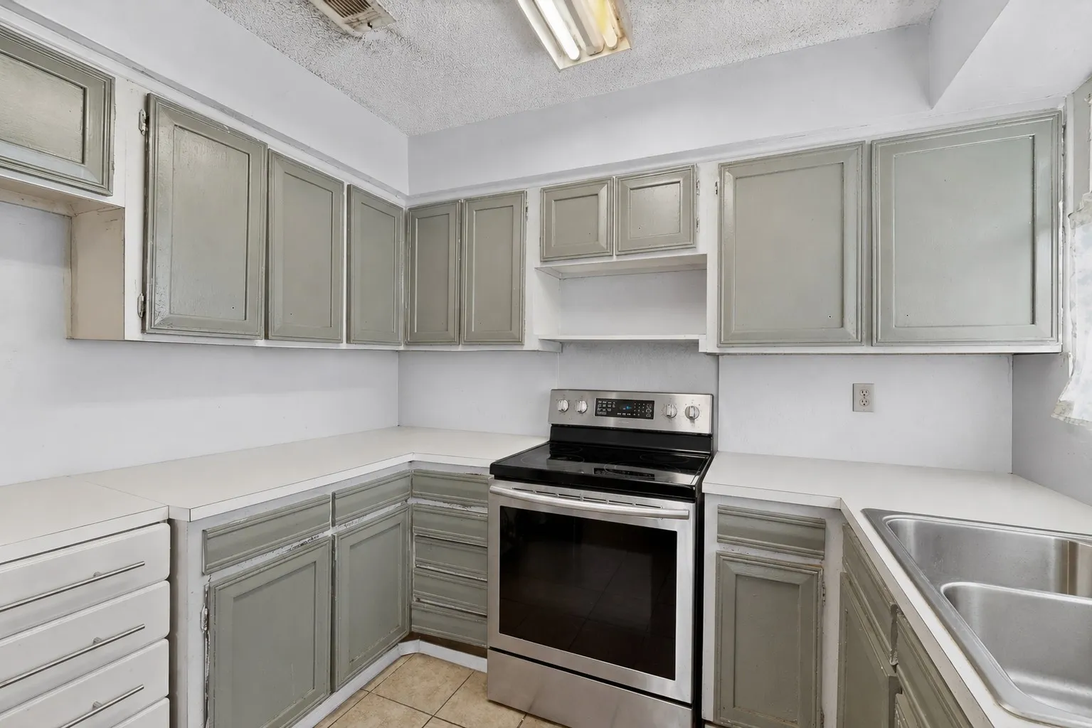 Kitchen featuring U-shaped countertops, stainless steel range, double basin sink, and ample cabinetry