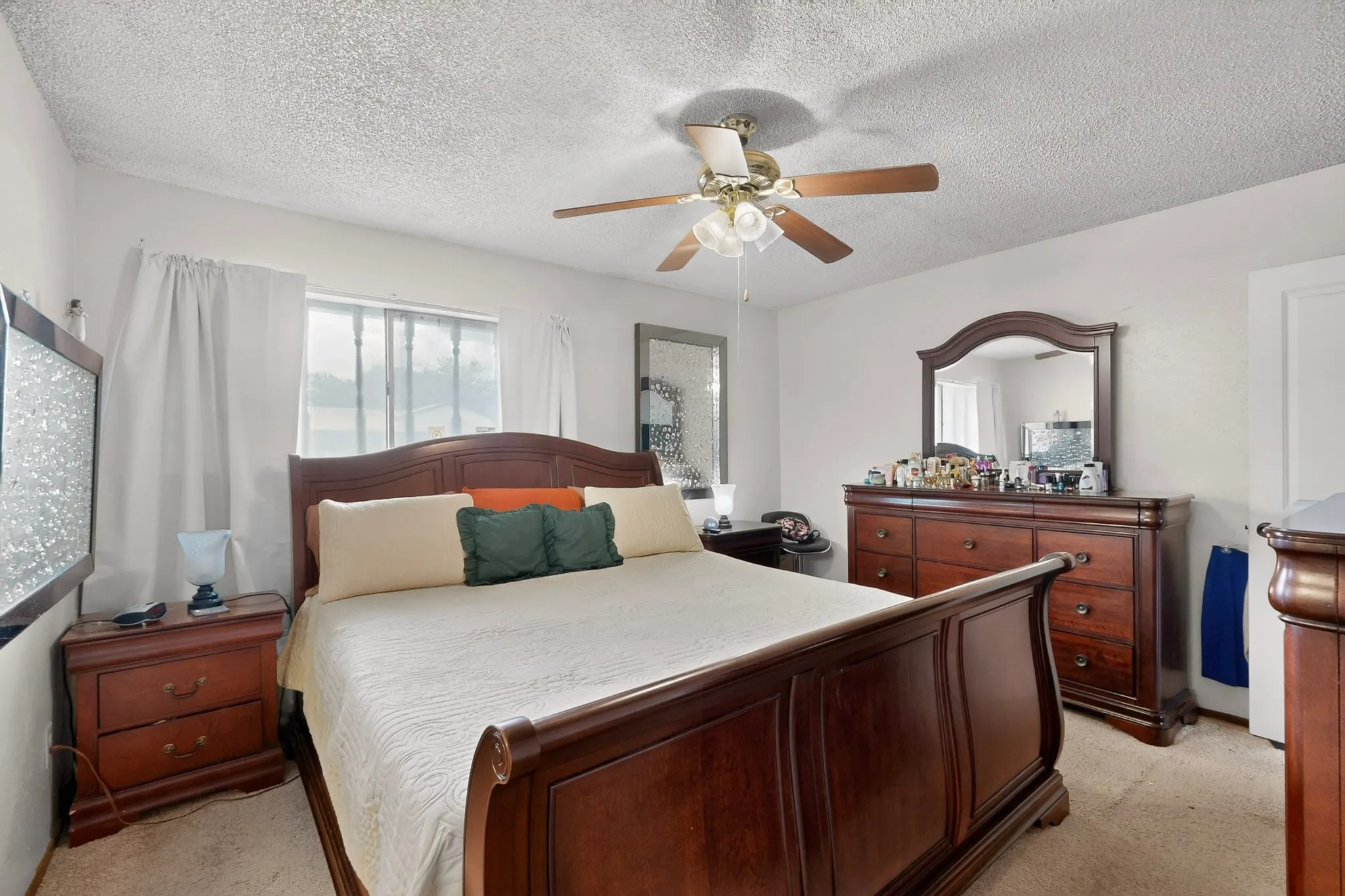 Bedroom featuring a ceiling fan with light fixture, window with privacy blinds, and light-colored carpet flooring