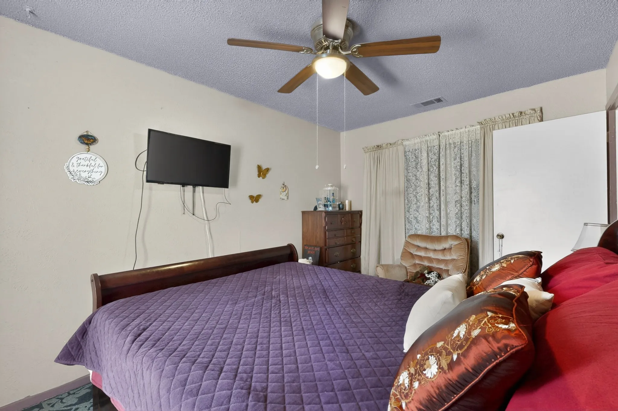 Interior room featuring a ceiling fan with integrated lighting, wall-mounted television, and neutral wall paint