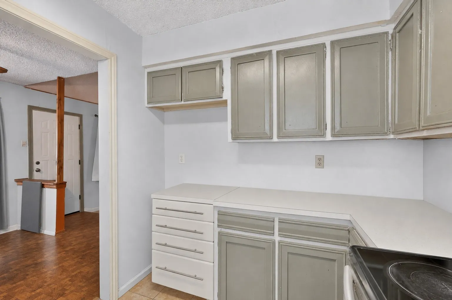 Kitchen featuring light gray upper and lower cabinetry, white countertops, a built-in cooktop, and tile flooring